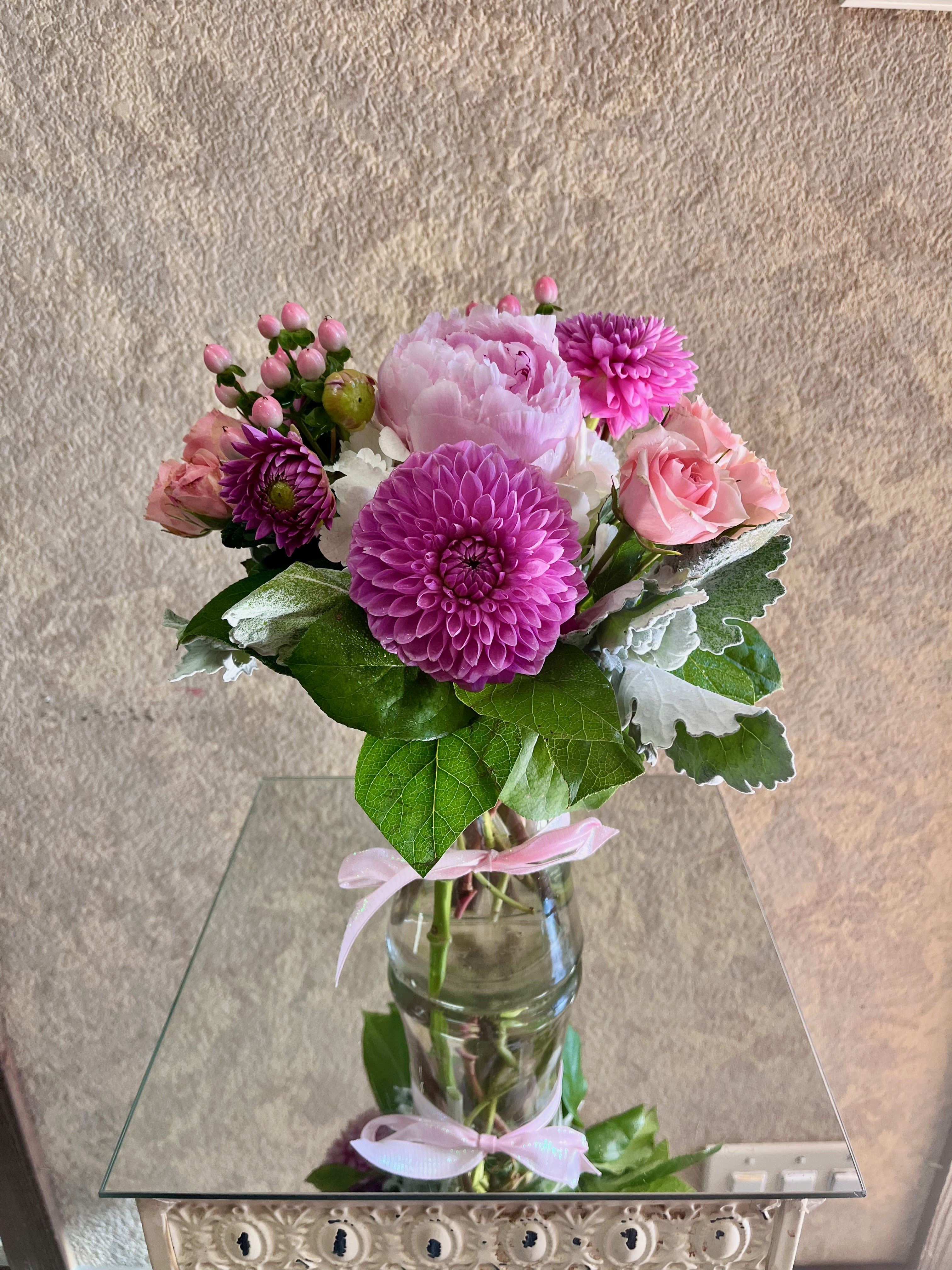 Pretty Peony and Dahlias - This bouquet is sweet and full of seasonal flowers that will surely brighten someone's day!  Type of Flowers: Peony, Dahlias, Spray Roses, Hydrangae, Hypericum Berries, and Dusty Miller in a short clear vase and bow. Availability: Seasonal Substitute Available: Yes Design View: All Facing View Photo shown: Standard  