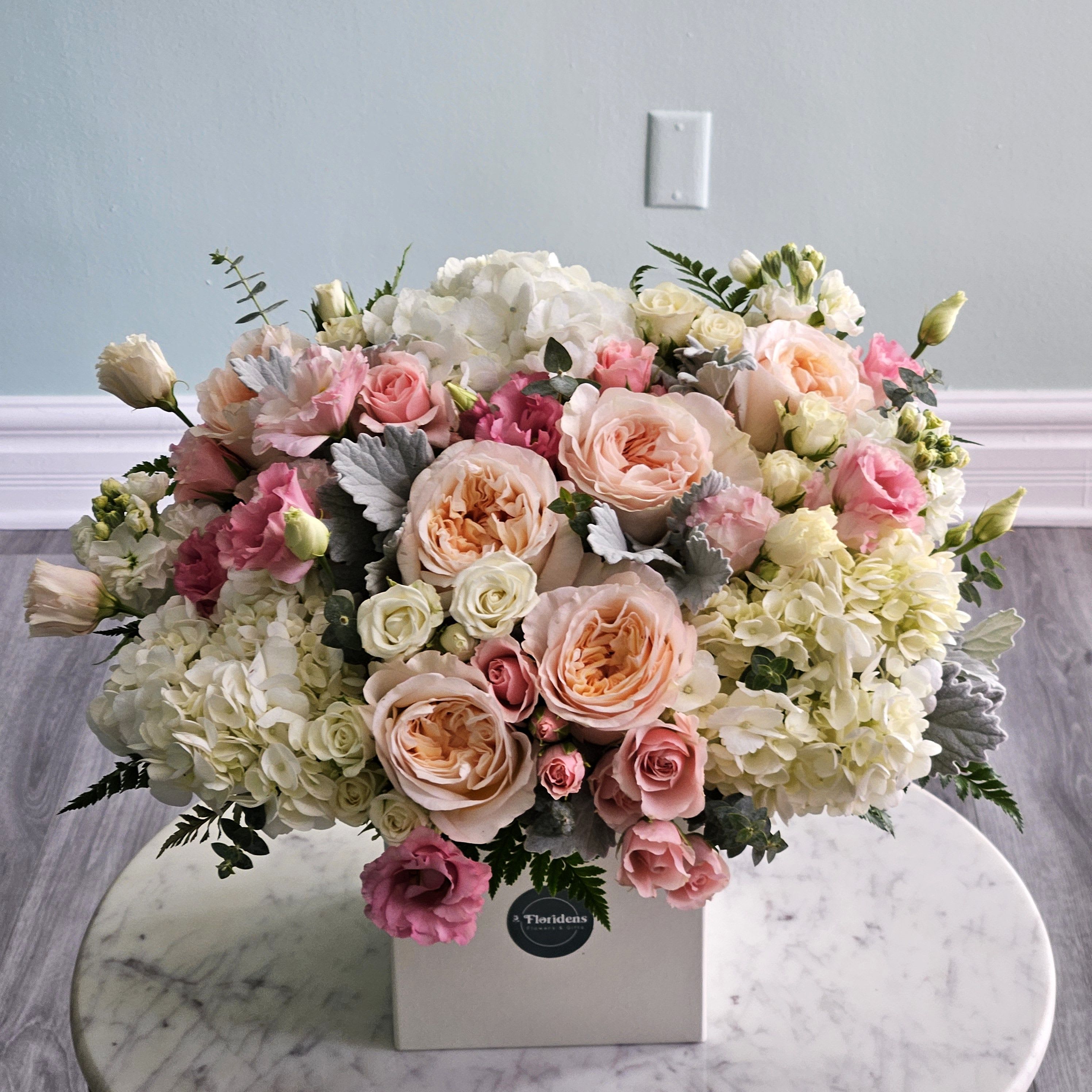 Cloud 9 - Float on air with our stunning Cloud 9 arrangement - a perfect blend of elegance and charm. Featuring fluffy white hydrangeas, delicate pink and white roses, lisianthus, and fragrant stock, this design radiates softness and sophistication.  The combination of pastel tones and lush textures creates a dreamy display that feels both timeless and romantic. Whether you’re celebrating love, friendship, or a special milestone, the Cloud 9 arrangement is a heartfelt way to brighten any space or occasion.