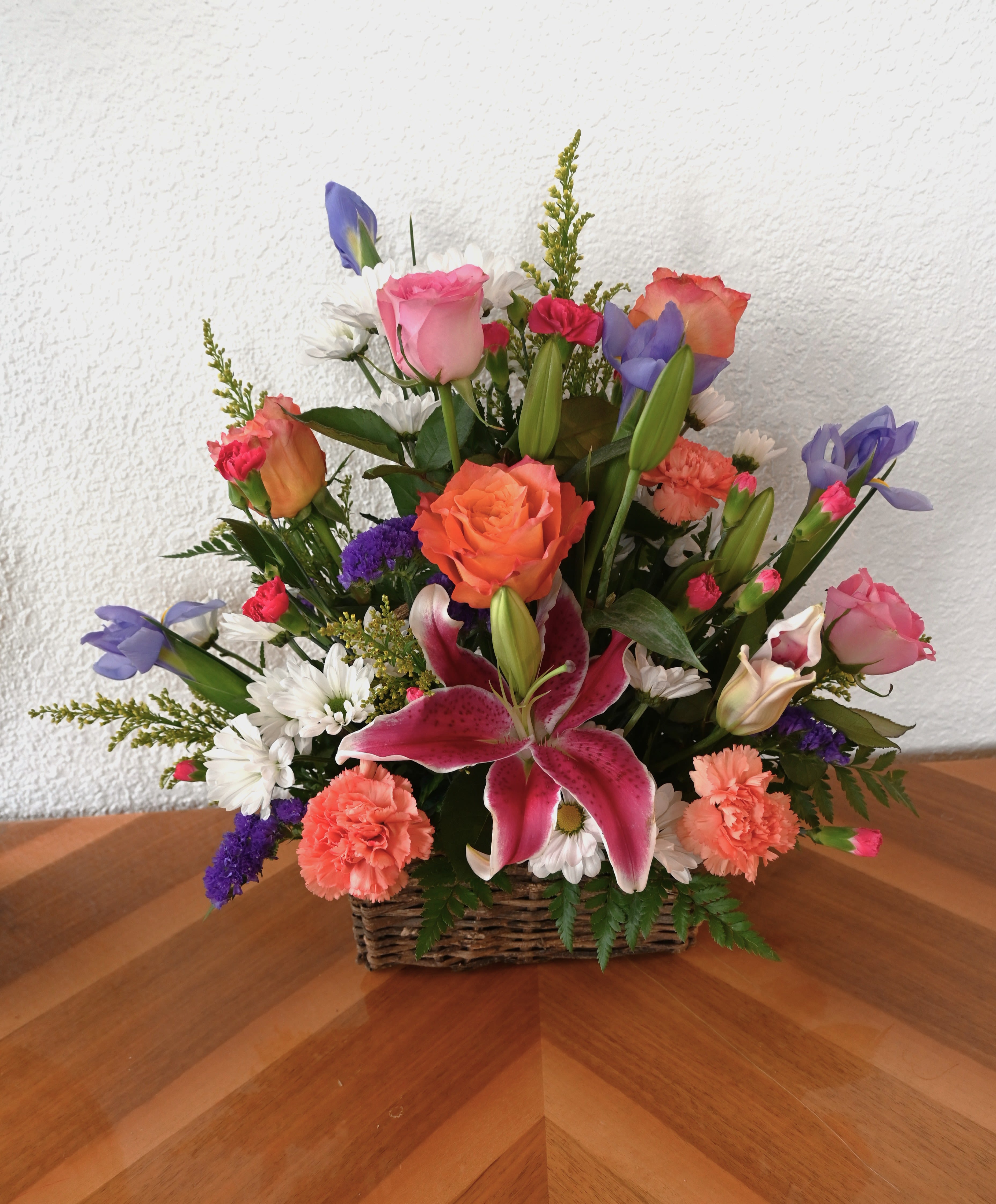 Blessings Abound - This bright and uplifting bouquet is a cheerful collection of pink lilies, orange and pink roses, iris, and daisies. The beautiful display of bright color is perfect for sending a message of support, sharing love, or just brightening their day.