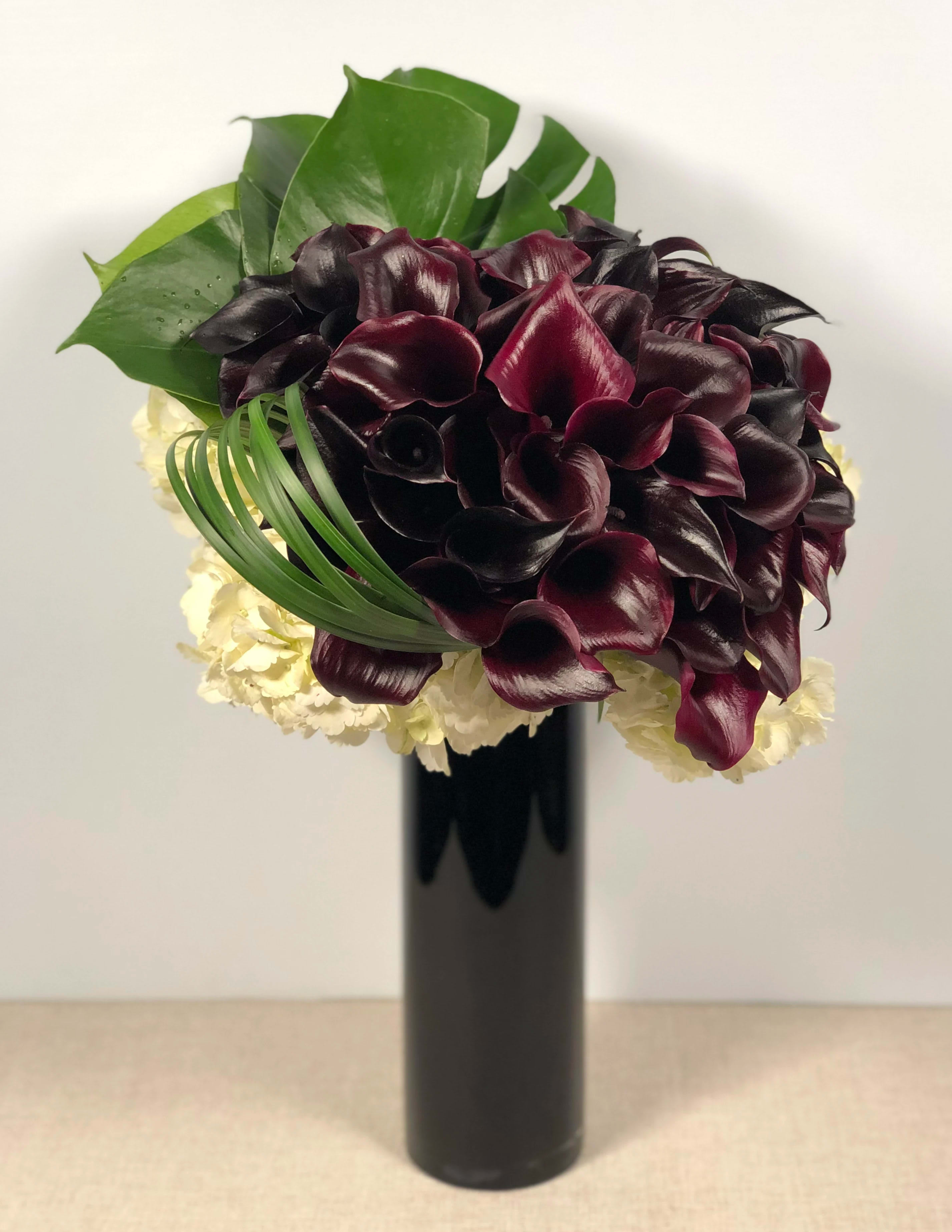 Aubergine Melt - A stunning and ultra chic arrangement that truly highlights the beauty of dark calla lilies. This sexy piece is perfect for a statement piece for your home or office, or the ideal gift for the discerning eye.