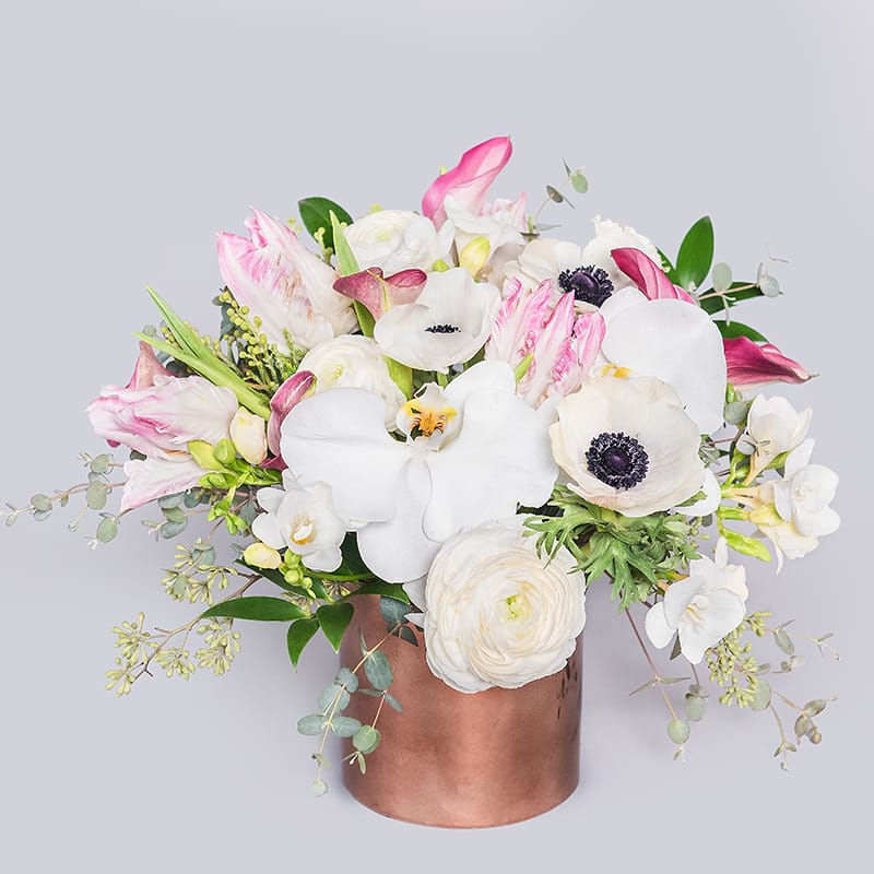 Moscow Mule - A sweet little arrangement in a bright copper color vase. Full of Parrot Tulips, Phalaenopsis Orchids, Anemones, Freesia, Ranunculus and mini Calla Lilies, this darling gift is perfect to enjoy any time of the year!