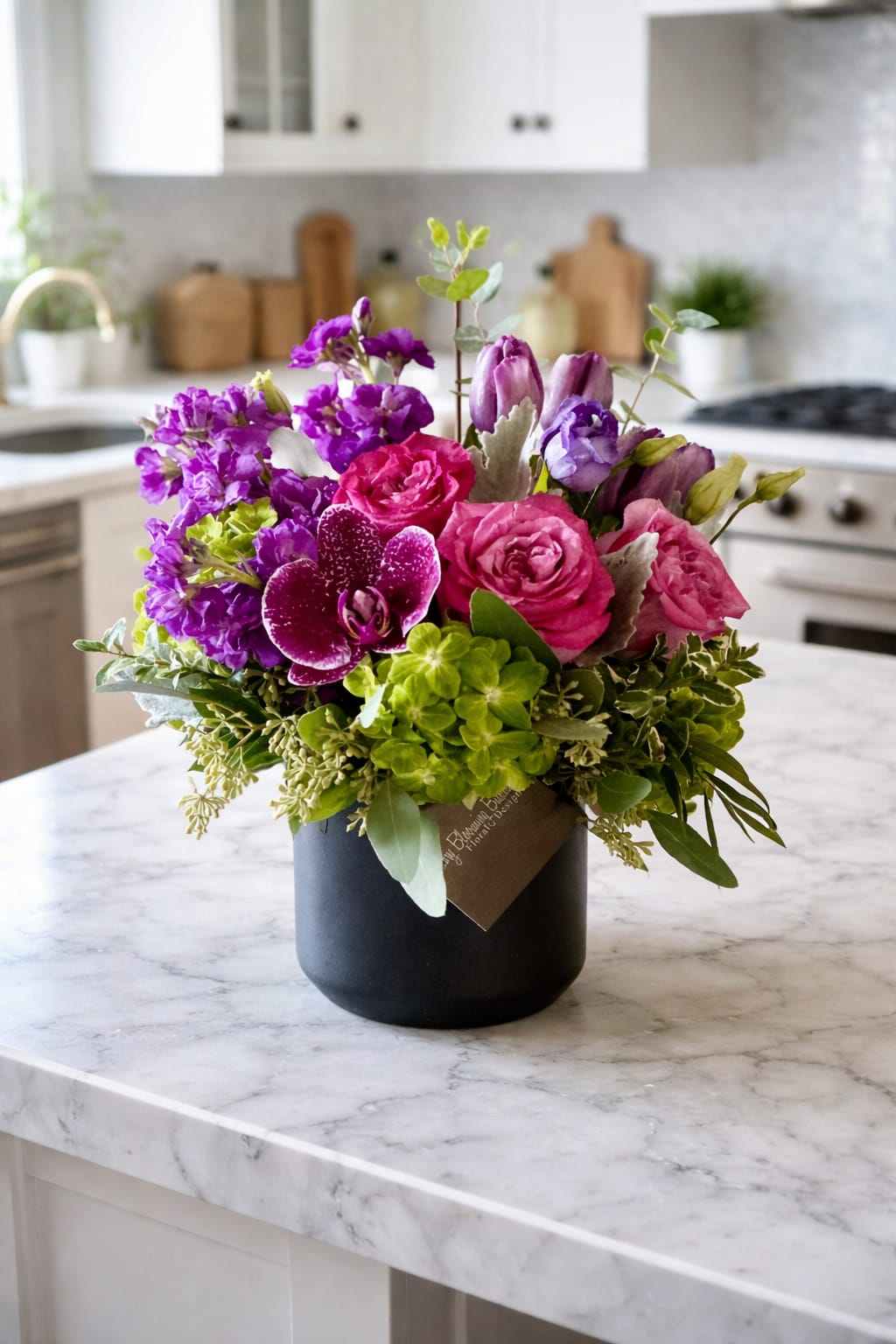 Confetti Garden - Bright, bold, and bursting with personality, Confetti Garden is a celebration in bloom. This vibrant arrangement blends lush hot-pink roses, playful purple blooms, a striking orchid, and fresh seasonal greenery—artfully designed to feel joyful, modern, and effortlessly chic.  Styled in a sleek matte black vase, Confetti Garden brings a pop of color and happiness into any space. It’s the perfect choice for birthdays, congratulations, thank-you gifts, or simply sending a little fun “just because.” Each arrangement is thoughtfully handcrafted to feel lively, uplifting, and full of charm—just like a handful of confetti tossed into the air.  Perfect for: Celebrations • Congratulations • Thank You • Just Because • Brightening a Home