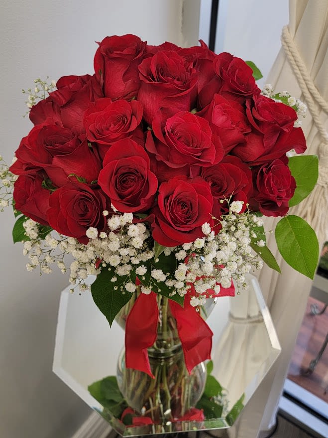 24 Red Roses arranged in a Spring Garden Vase  - 24 Long stem Red Roses uniquely and tightly arranged with babies breath and light greenery in a spring garden vase. The vase is tied with a matching red bow. 