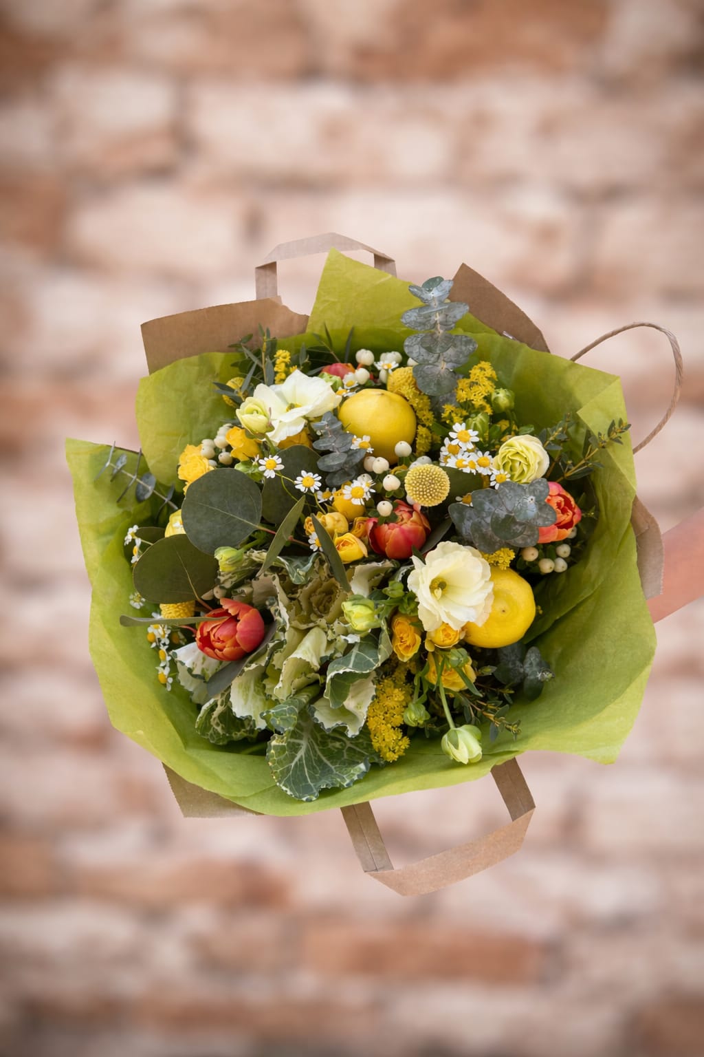 Lemonade Stand - Hand-tied bouquet in bright yellow hues with fresh lemons, butterfly ranunculus, and kale wrapped in up-cycled paper grocery bags. A perfect gift to celebrate a loved one or brighten a cloudy day. This bouquet looks and smells like a sunny summer day. 