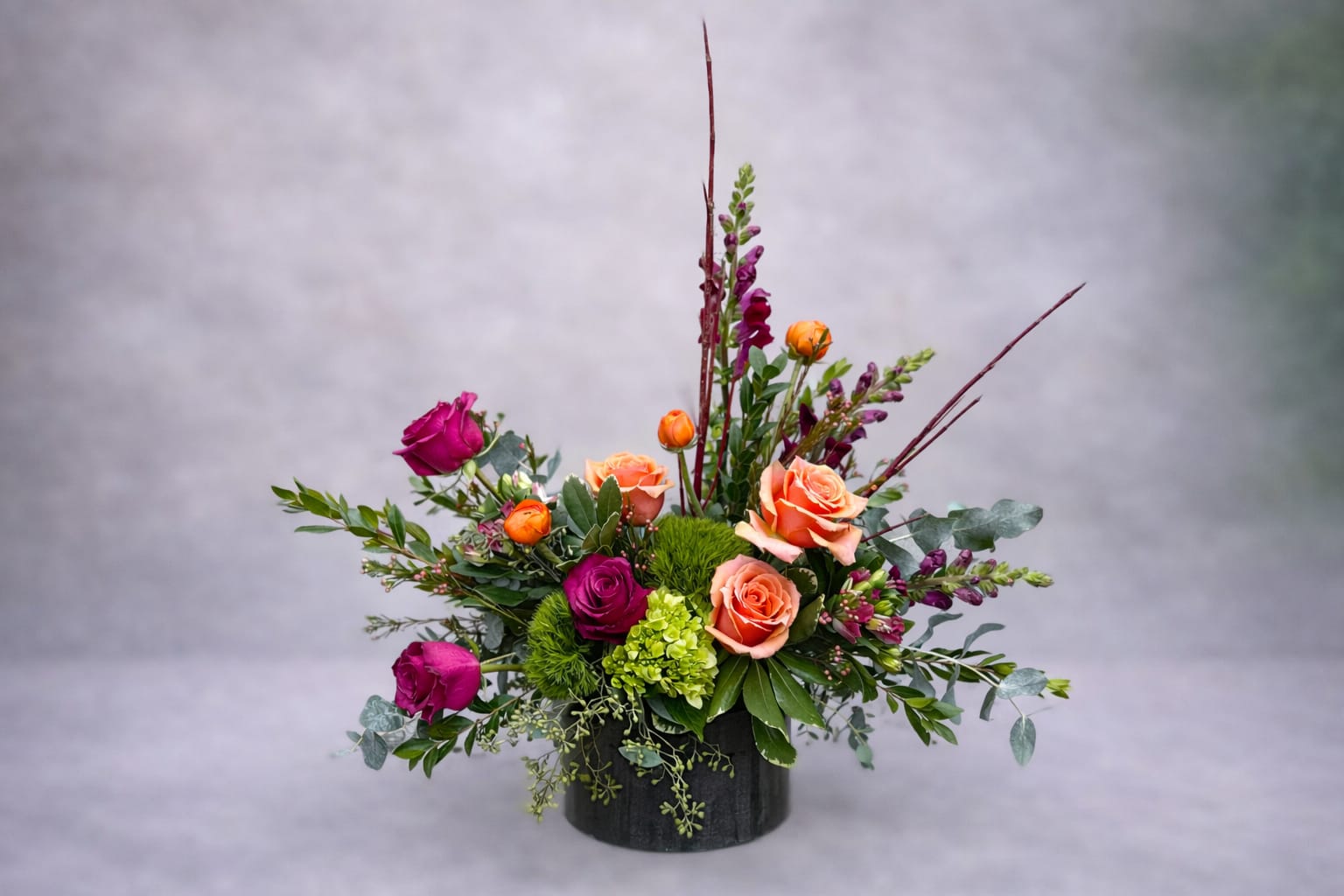 Rusted Rose - Like an heirloom rediscovered, Rusted Rose speaks to the beauty of imperfection and the poetry of time. Coral and wine-toned blooms meet the earthy textures of moss and foliage, creating a harmony between decay and renewal. Every petal feels sun-warmed and storied, evoking the faded glow of autumn afternoons and antique metal kissed by years.  Rusted Rose is both strength and softness — a piece for the dreamers, the collectors, and those who find elegance in the undone.