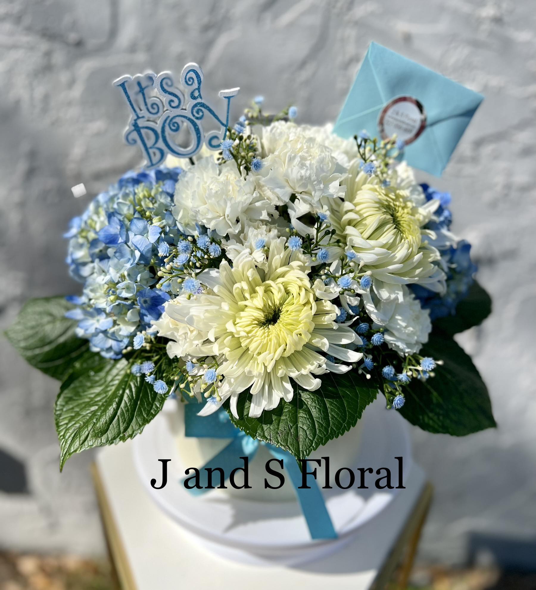 Baby Blue  - introducing Our New Design Baby Boy , beautifully arranged with mums, hydrangeas, fillers and greenery. It can be made with pink for a baby girl. 