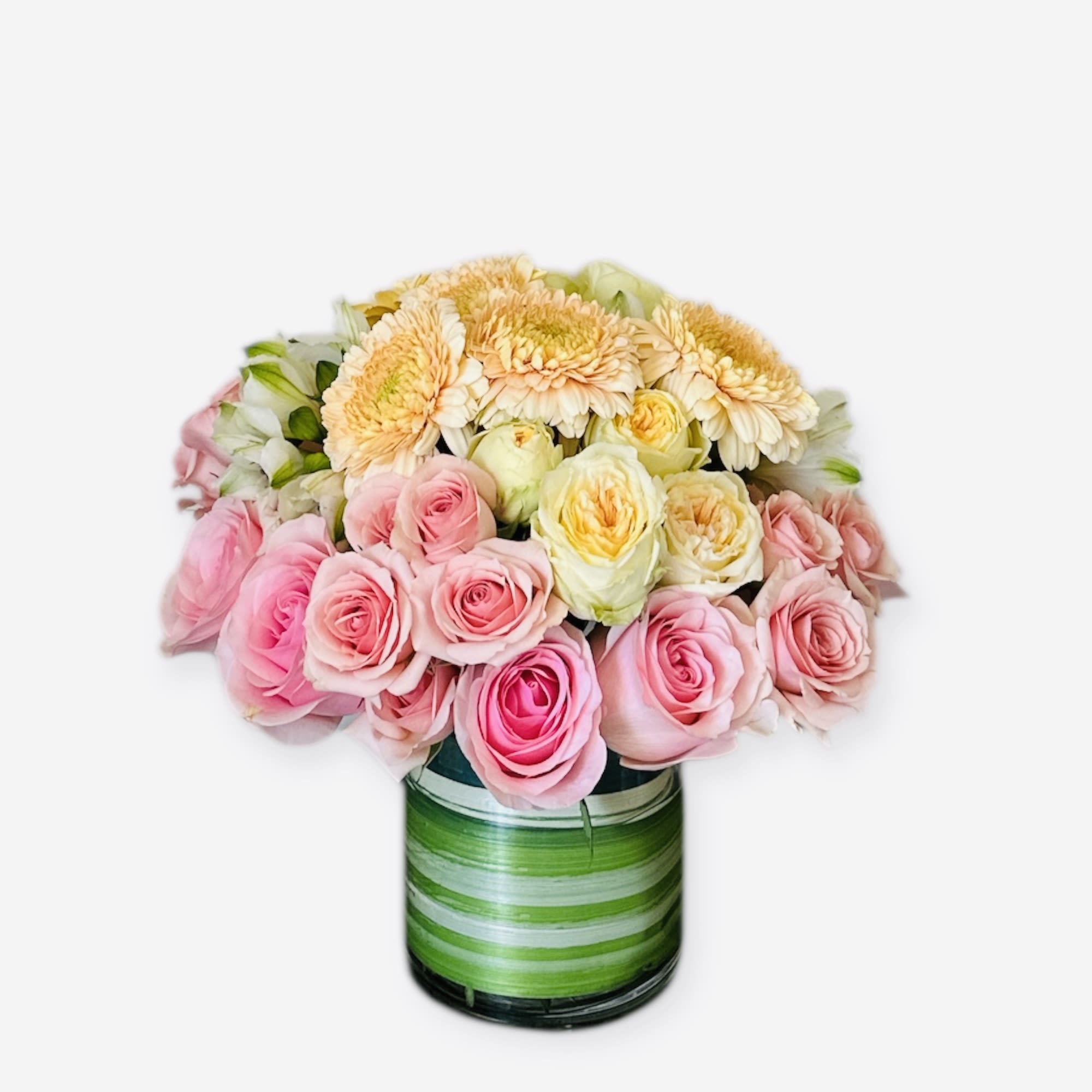 La Créme - Soft, elegant, and irresistibly sweet—La Crème is a graceful floral arrangement of blush roses, buttery yellow garden roses, and pale peach Gerbera daisies. Artfully arranged in a clear vase wrapped with striped  green leaves, it’s the perfect gift for birthdays, anniversaries, or simply to brighten someone’s day with creamy pastel charm. 