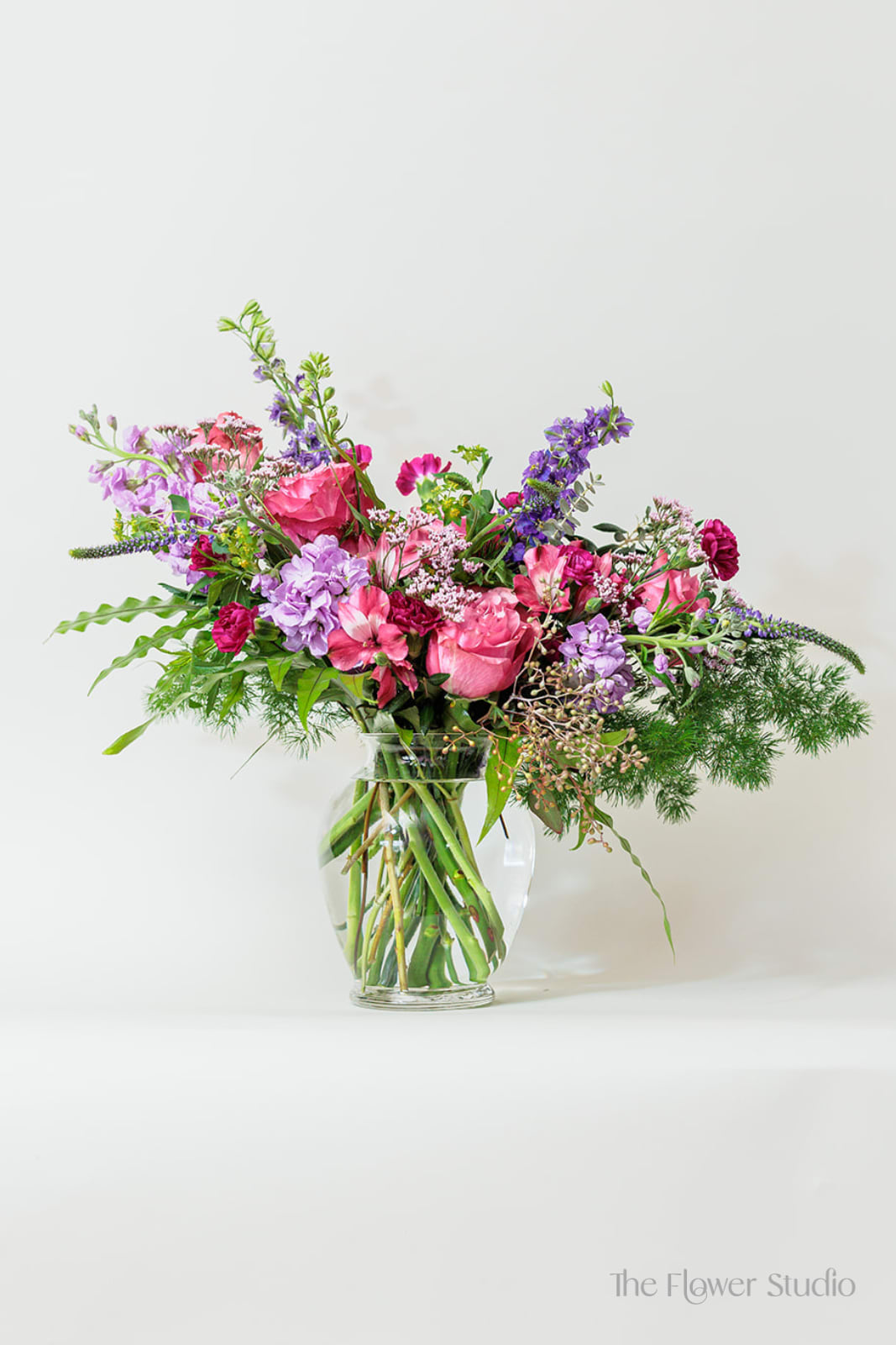 Shades of Purple - Soft yet striking, this beautiful arrangement combines soothing lavender hues with rich purples for a truly enchanting display. This arrangement is perfect for bringing a serene and elegant vibe to any space or occasion! Approx.  H19” x W21” 