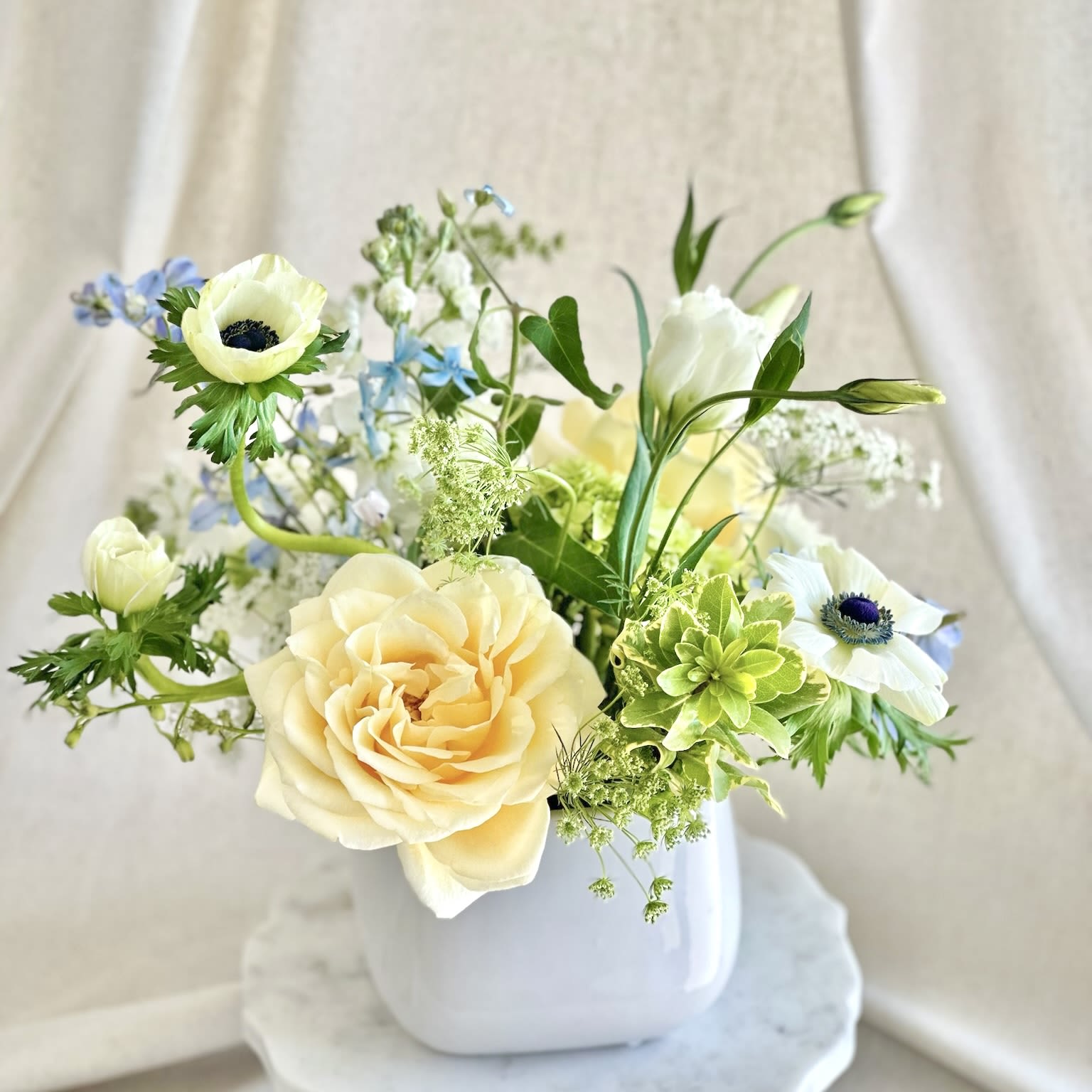 Il Cielo  - White and blue arrangement in a white vase.  Flowers may vary by season.