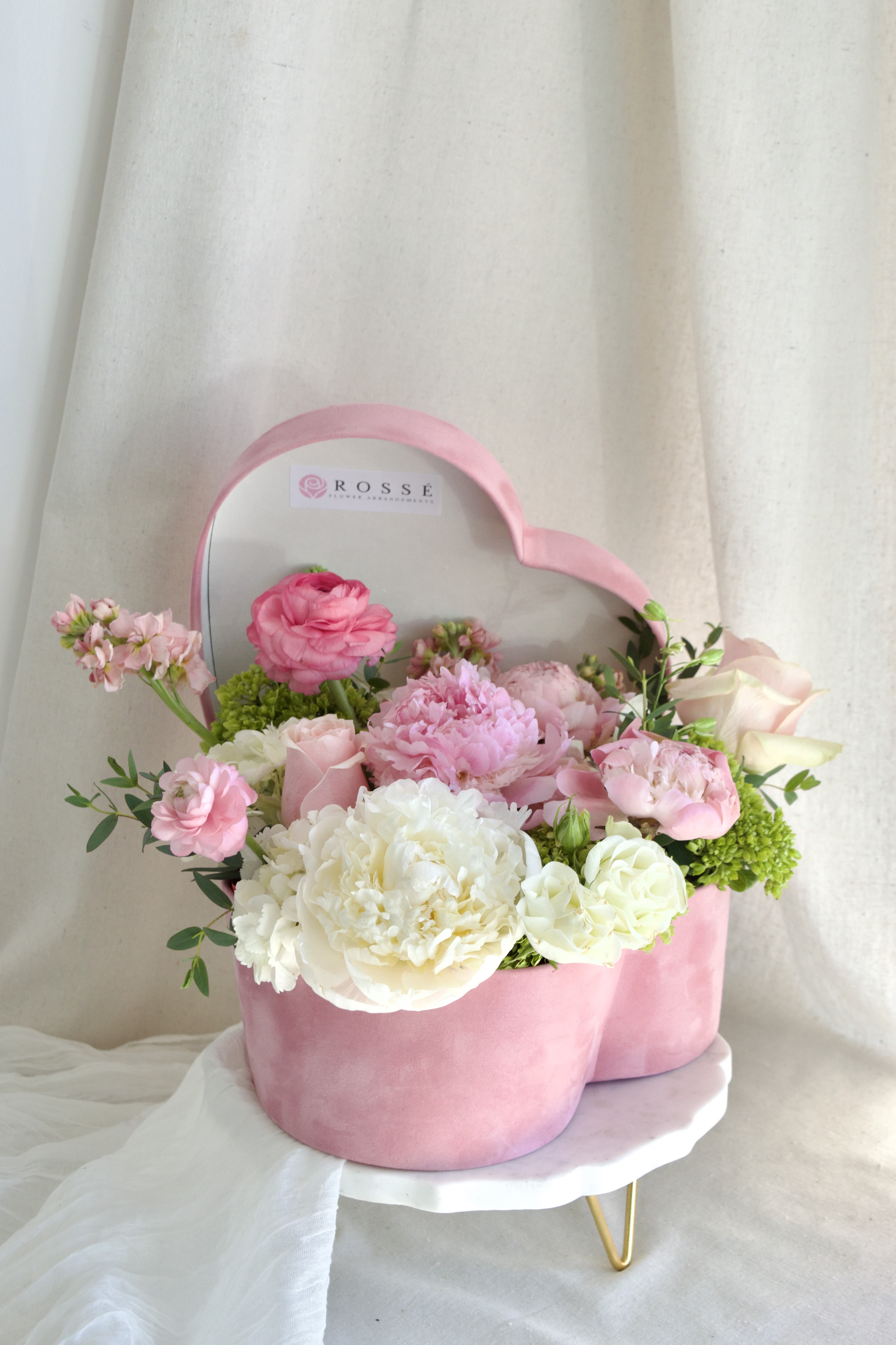 Pink Garden  - A heart-shaped pink velvet box filled with white, pink, and green flowers.   Flower types may vary depending on the season.