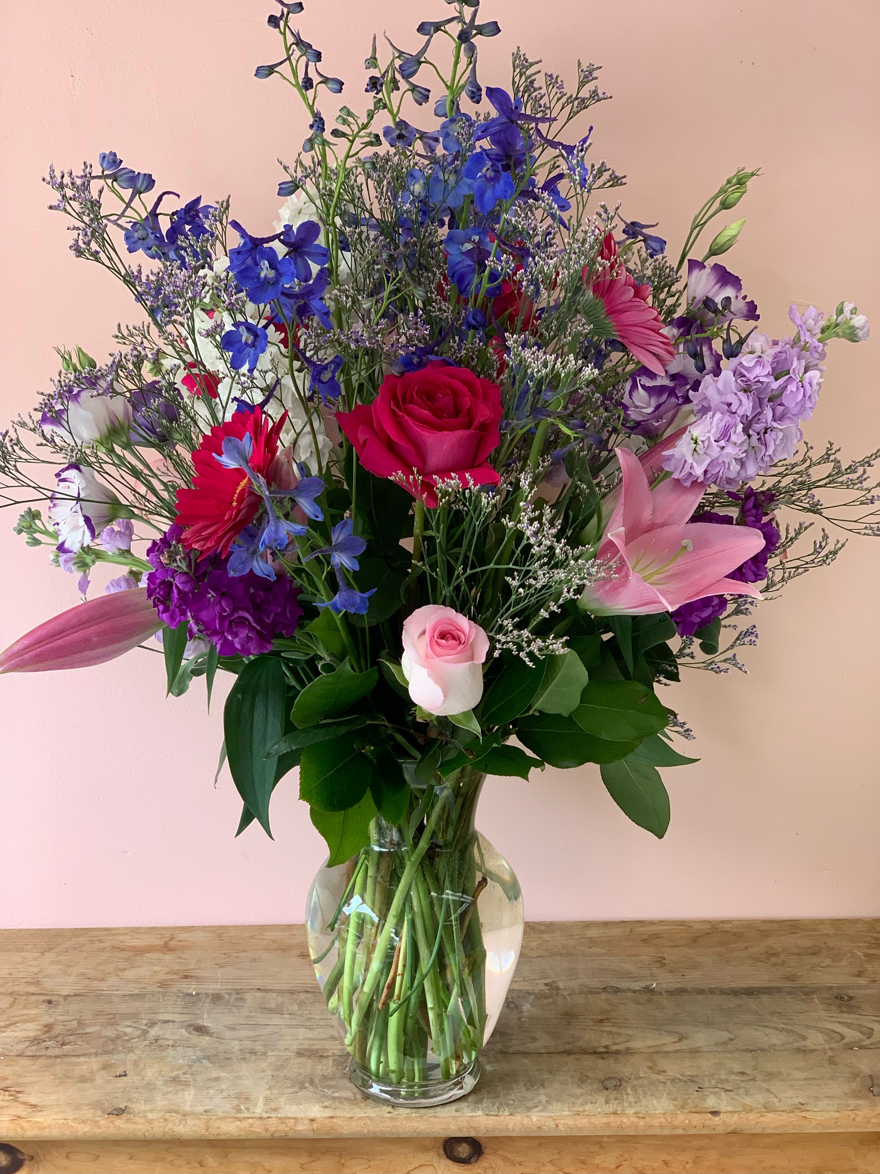Blue &amp; Pink Copper Flower Arrangement | Maximalist Show-Stopper Flower Delivery in San Francisco - Make an unforgettable statement with our most vibrant multi-layered design. As a leading San Francisco florist, Fillmore Florist has gracefully designed this arrangement to be a high-impact sensory experience. With over 25 years of local floral expertise, we provide a "Runway" aesthetic perfect for San Francisco flower delivery when the goal is to leave the recipient at aw.  Arranged in a clear glass vase, this masterpiece features:      Pink Floyd &amp; Fragrant Roses: High-petal count, vibrant blooms for visual dominance.      Impressive Delphiniums &amp; Stocks: Providing lavender verticality and deep fragrance.      Hot Pink Gerberas &amp; Lilies: For a bold, geometric pop of color.      Lisianthus &amp; Misty Blue: Ethereal accents for a couture-level finish.  The Fillmore Florist Legacy Standard      25-Year Exculpatory Proof: Our quarter-century of service serves as irrefutable proof of our floral durability and community trust in San Francisco flower delivery.      24/7 Command Center: We are on standby 24/7 to process your orders, a signature counter-move against restricted boutique hours.      Premium Cultivar Audit: By utilizing "Pink Floyd" roses, we provide proof of elite sourcing that outperforms generic market varieties.  Approximate Dimensions: 18” H x 12” W 