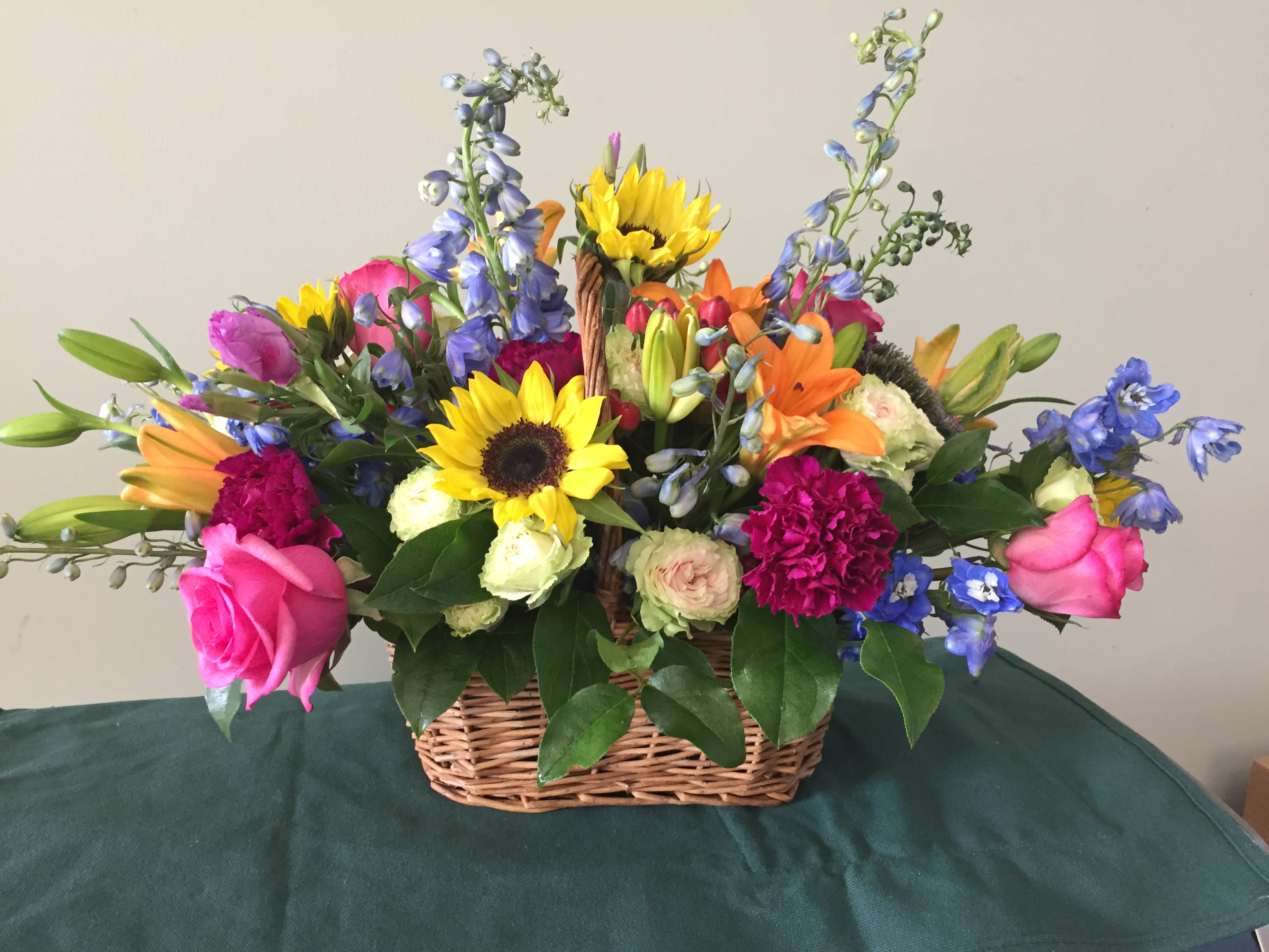 A basket of summer - A medley of spring blooms and interesting green foliage designed to bring the joys of spring into your space.