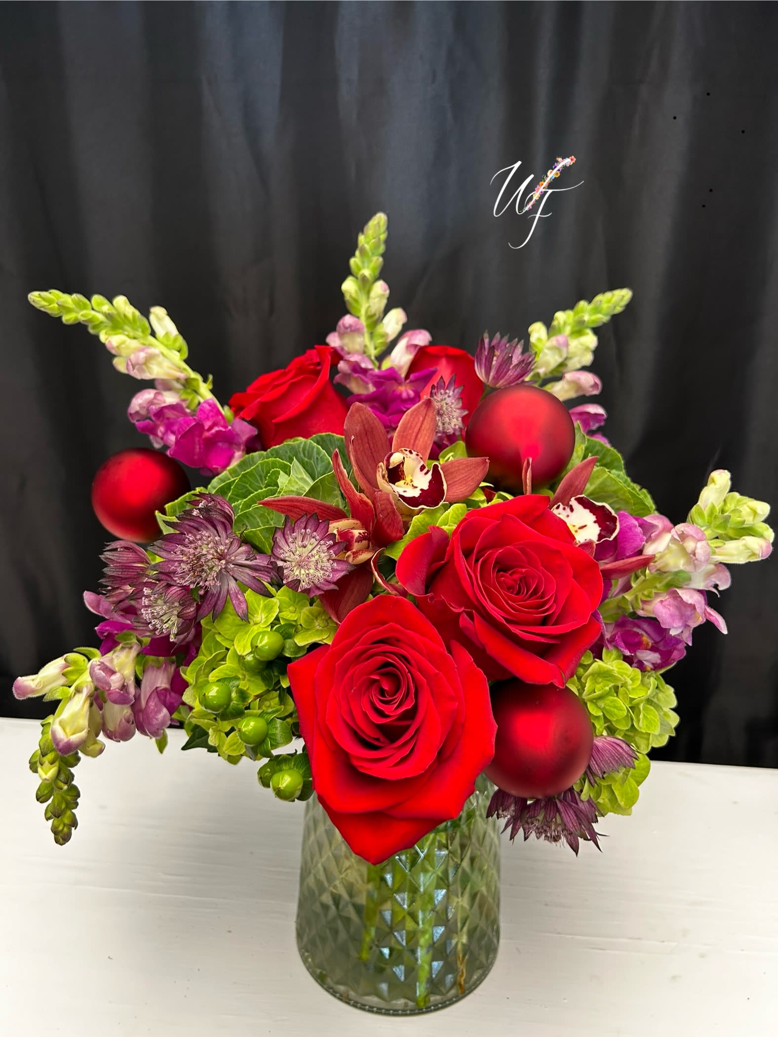 Red roses and purple flowers in a glass vase with red ornaments