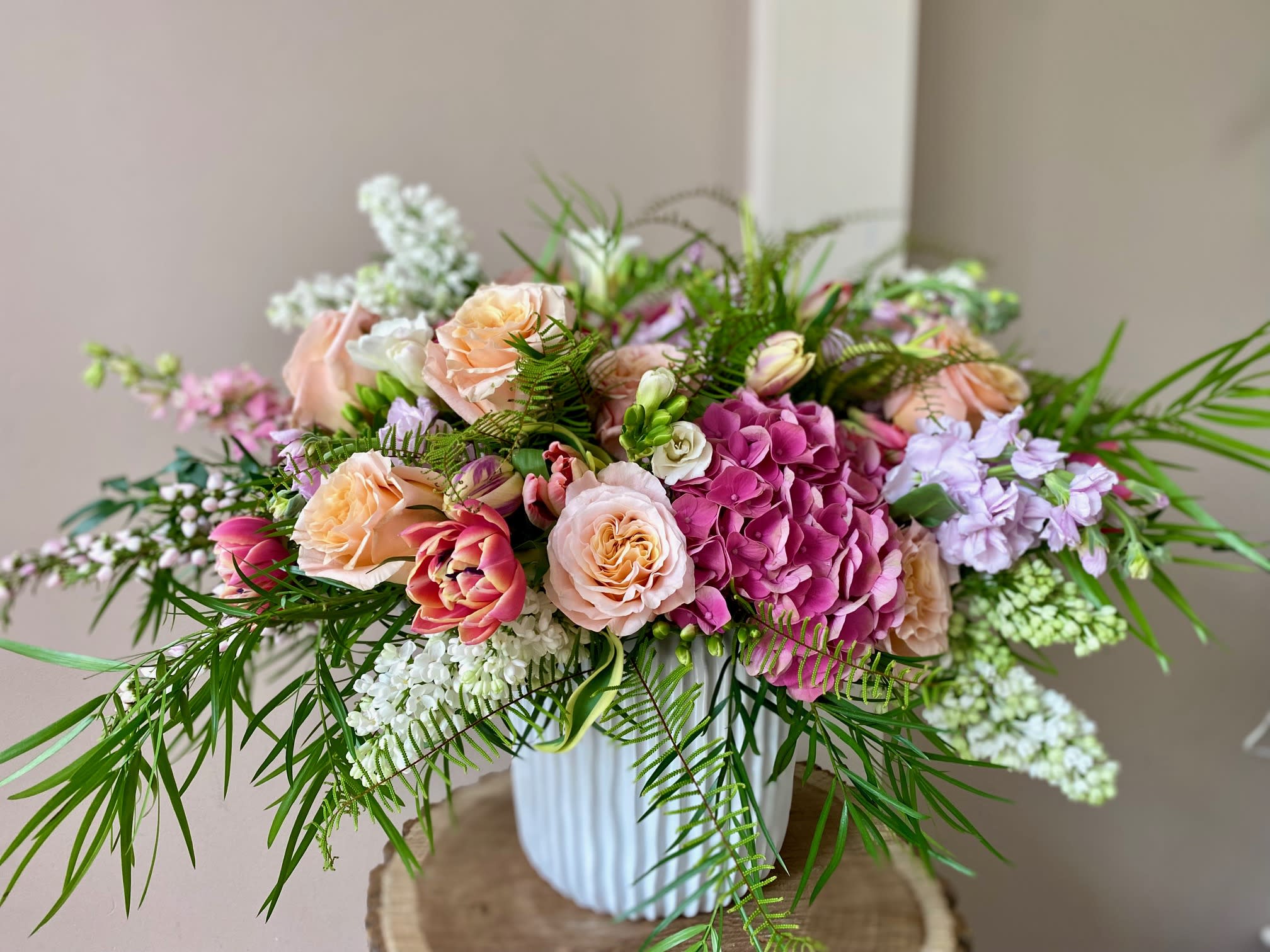Sweet as a Peach - Wow! This arrangement will deliver nothing less but a big peachy WOW! Loaded with gorgeous peach roses, high-end Dutch hydrangeas, fragrant freesia and lilac (only while in season!!!), luxury double blossom aka "mini peonies" tulips and more! Comes arranged in a ceramic vase. 