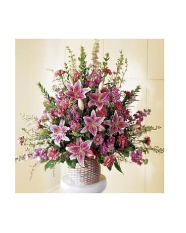 Leaf and Petal Basket - Stargazer lilies, soft pink carnations and larkspur, with lavender stock and daisy pompons, are designed in an abundant display.  In a wicker basket, it's perfect for the funeral home or for family members to take home.  Approx. 40''X 40''   Flowers and colors may be substituted depending on availability.   FCS16-3162