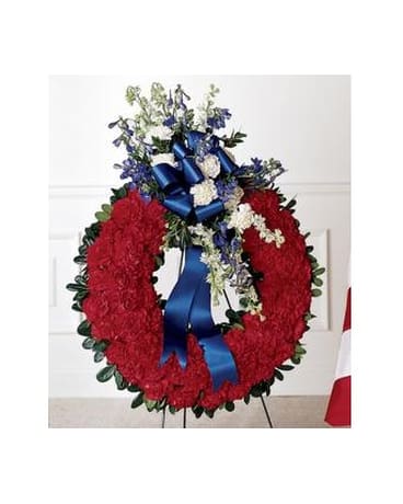 All American Tribute Wreath - This striking wreath of solid red carnations is accented with white larkspur and carnations blue belladonna and a blue bow.   FCS30-3179