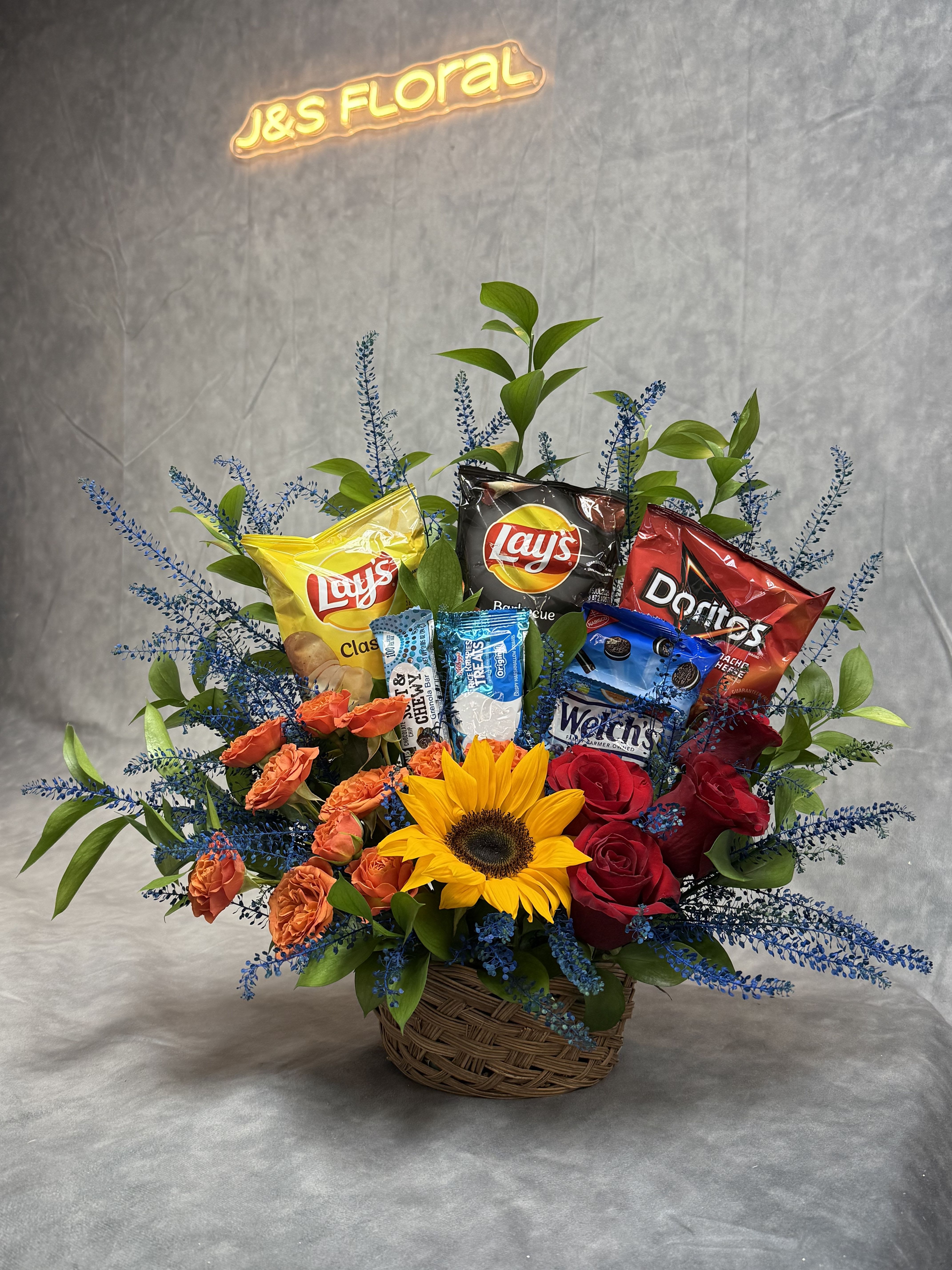 Bloom and Munch Basket  - Flowers for the heart, snacks for the soul. This basket is a perfect pick-me-up for any day worth celebrating — or just to send a little love. Snacks included will vary depending on current availability. 