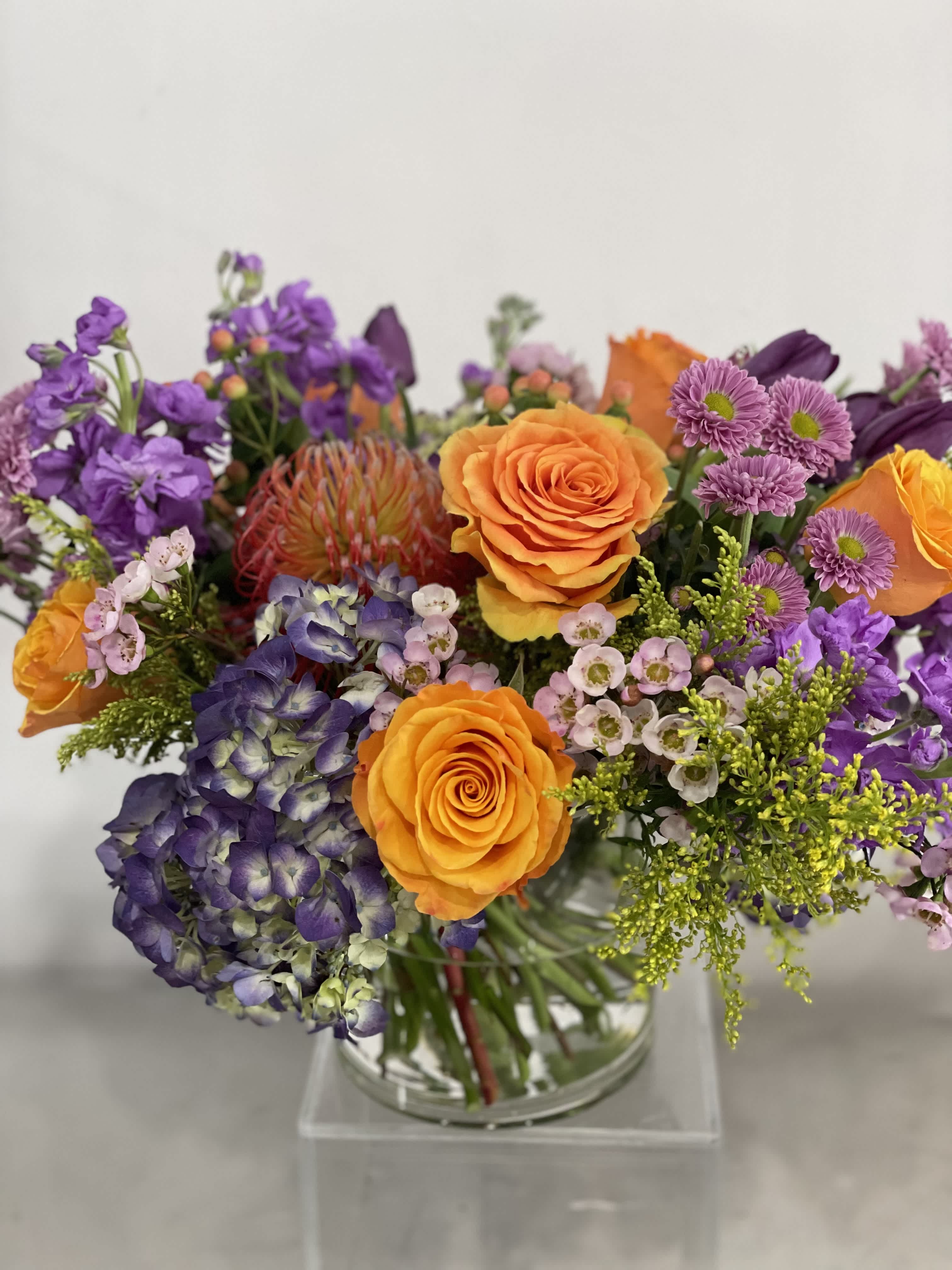 Pop of color  - The most gorgeous burst of color to brighten someone's day! We will fill a glass vase with the very best the market has to offer in premium flowers. Designers Choice in  purples. lavenders, and golden saffron. 