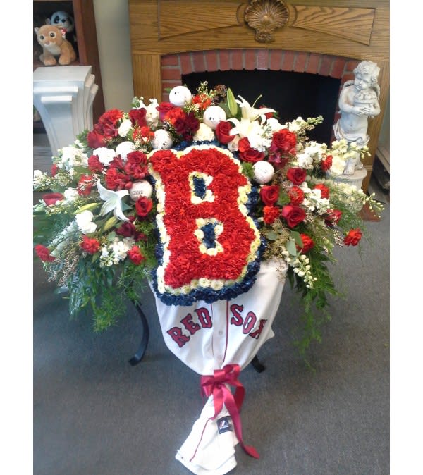 Red Sox casket spray  - This spray is placed on the casket, for the Red Sox fan.  An array of red roses, red carnations, white lillies, snapdragons, stock, etc. The floral spray is accented with baseballs. The Traditional Red Sox B is made out of fresh flowers. Need 48 hours notice (Shirt not including)