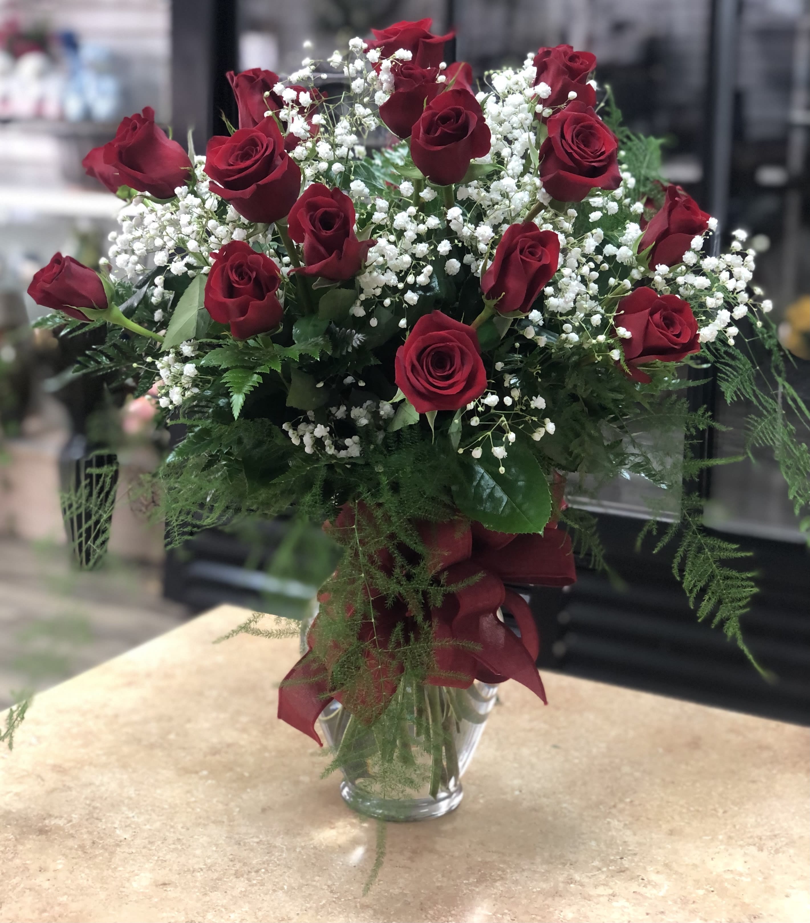 Long stem roses with baby’s breath.  - A dozen long stem red roses arranged in a glass vase with baby’s breath and a nice hand tied bow. NOTE- 24 ROSES PICTURED. 