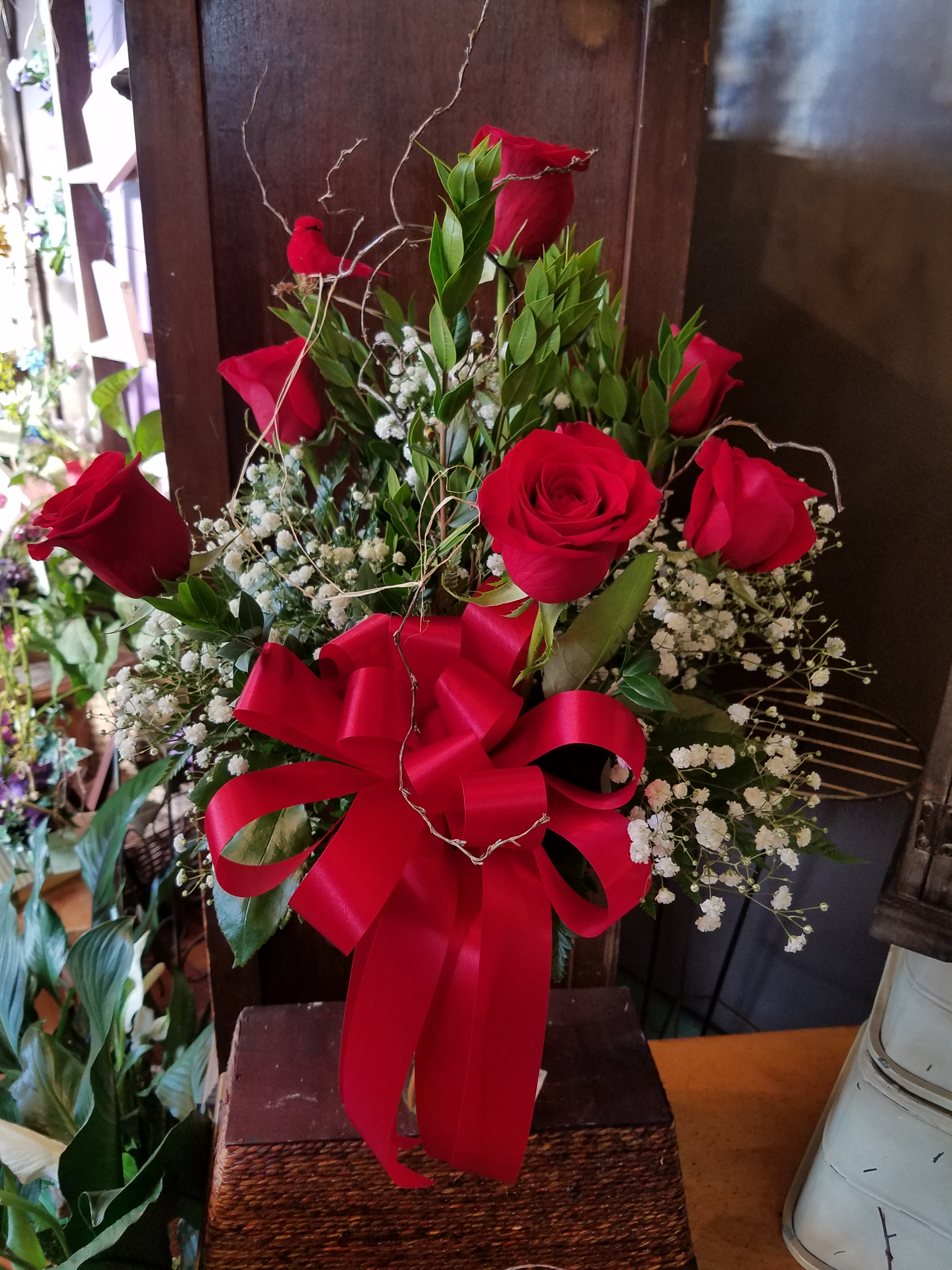 Eckert Florist's 6 Roses Arranged - This charming bouquet includes 6 roses accented with filler flower along with a satin ribbon. Delivered in a clear glass vase with our signature bird and branches. *Please specify choice of rose color in "Special Instructions". **Red roses will be sent if no specific color given.