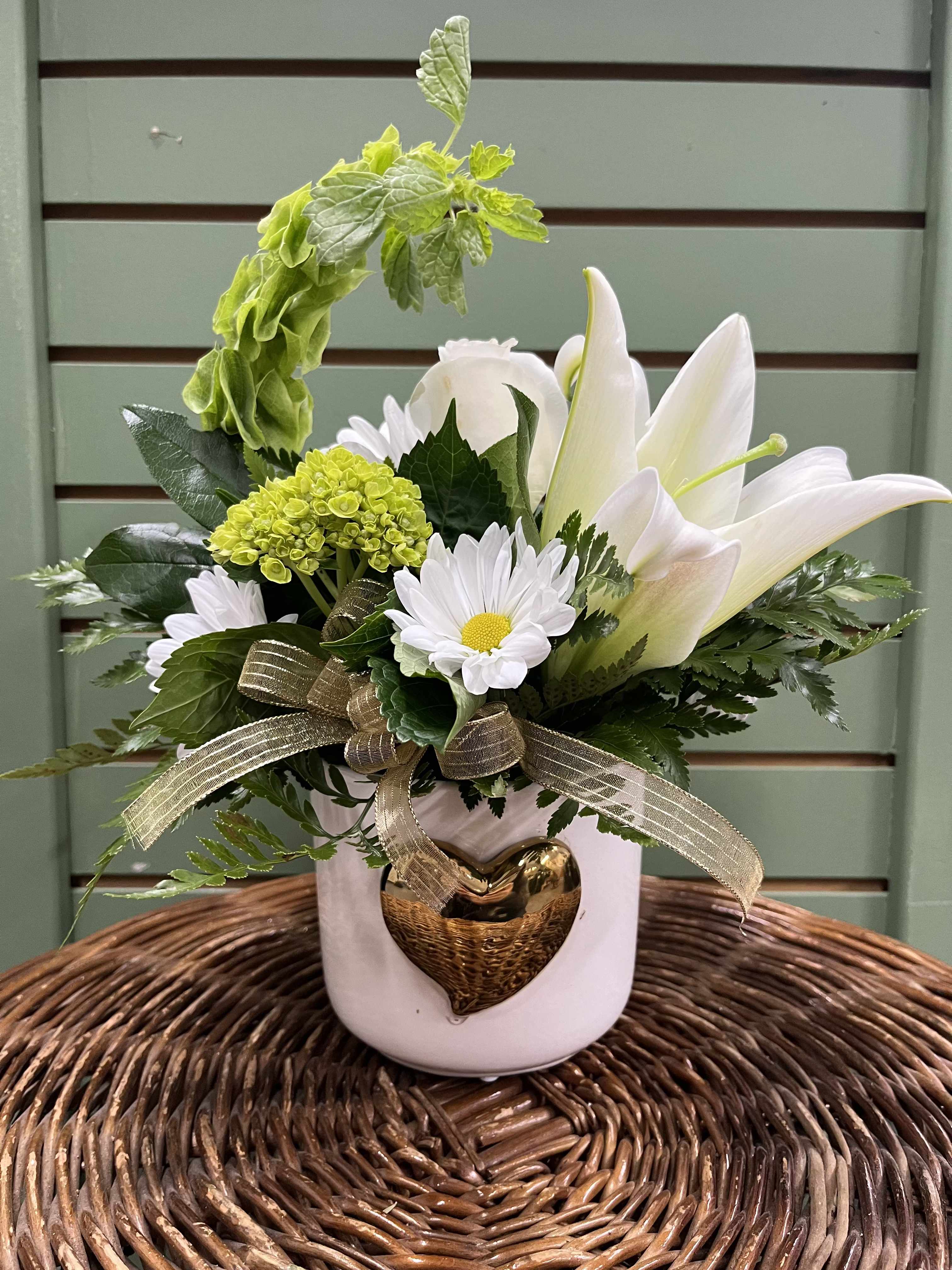 Heart of Gold - Show your love with this elegant bouquet which features a white lily, roses, daisies, a green hydrangea, and bells of Ireland in a beautiful gold heart container. 