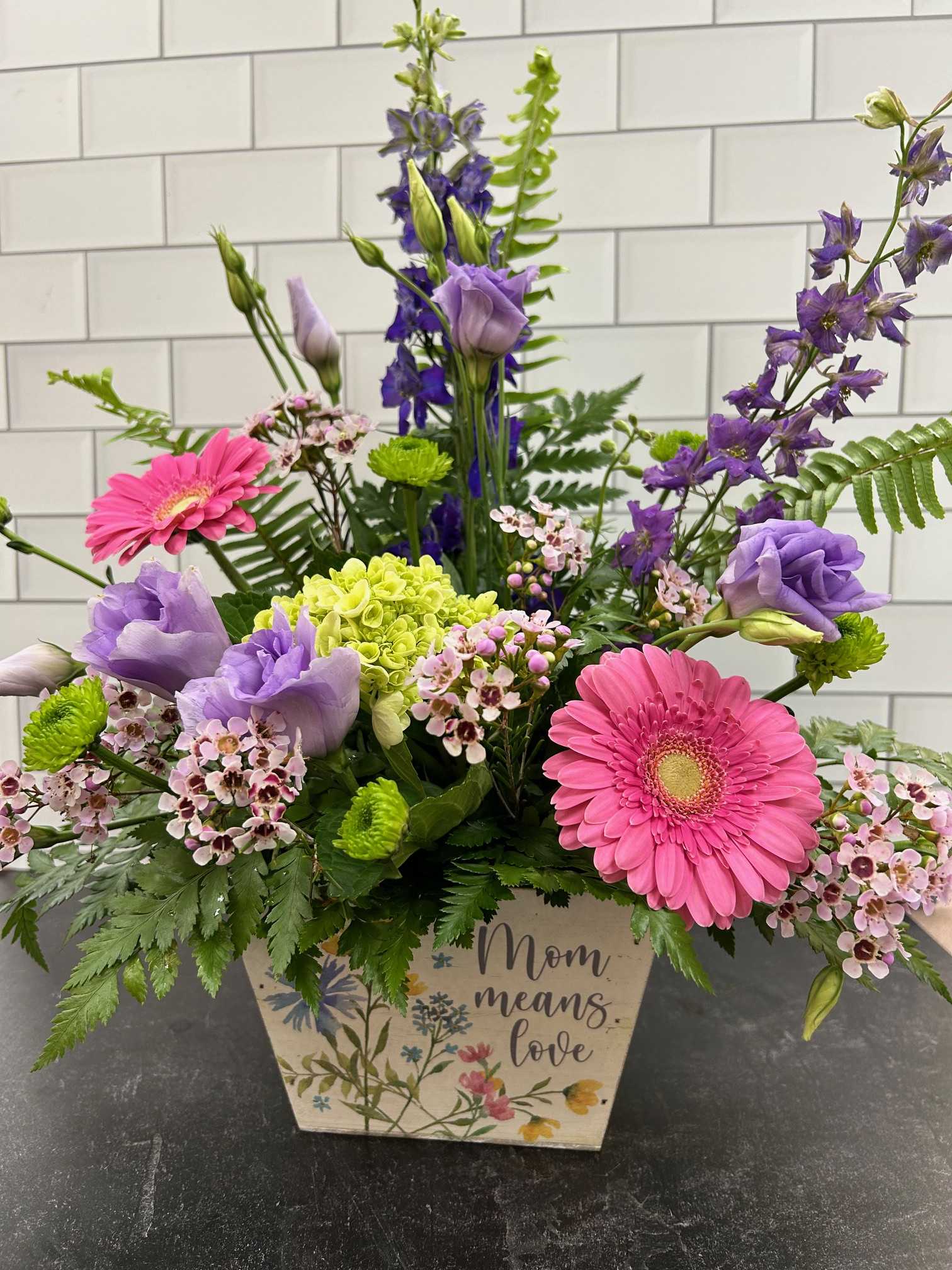 Mom Means Love - Send a keepsake for mom with this fresh arrangement in a decorated wooden box filled with cheerful colors of hydrangea, lisianthus, gerber daisies, wax flower and larkspur.