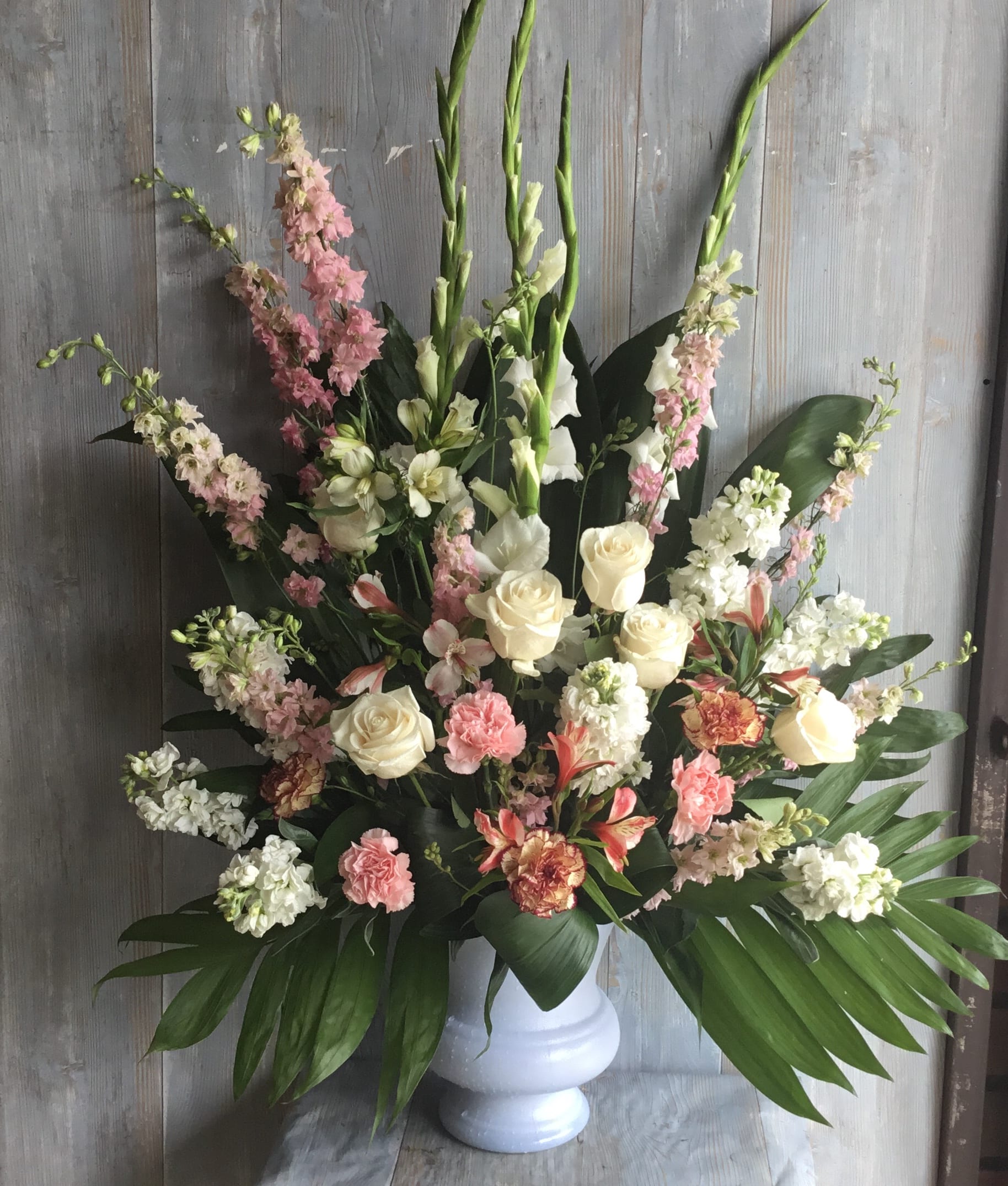 Faithful Urn - A large bouquet of flowers for the funeral service.  The white urn container is filled with gladiolus, roses, snap dragons and stock.