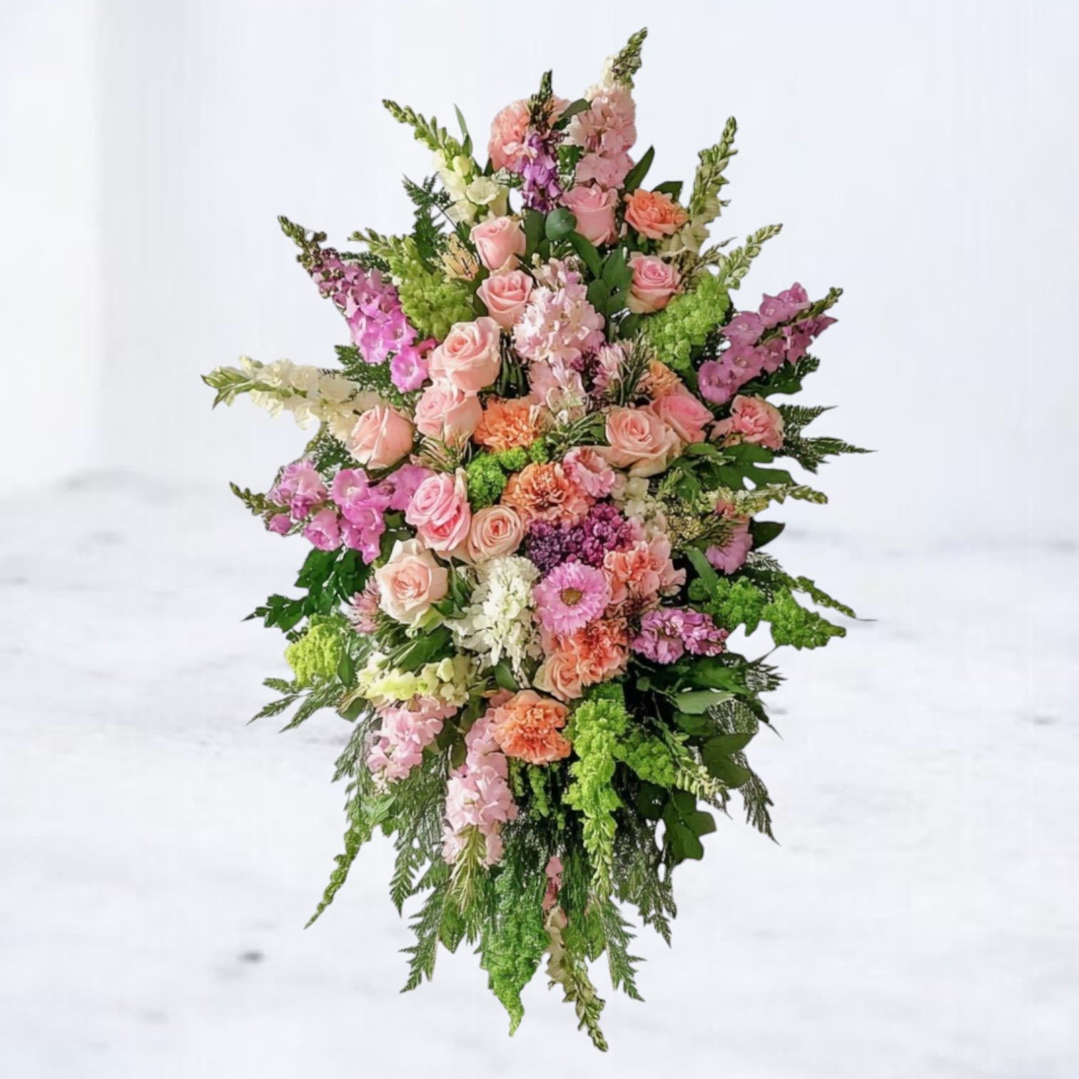 Garden of Peace Standing Funeral Spray - The Garden of Peace Standing Spray offers a heartfelt tribute with its blend of soft pink roses, peach carnations, lavender blooms, and fresh greenery. Designed in a graceful cascading style, this arrangement symbolizes serenity, love, and remembrance. Its pastel palette brings comfort and hope, making it a beautiful choice for funeral services, memorials, or graveside tributes. Available for same-day sympathy flower delivery in Magnolia, Tomball, Houston and surrounding areas, the Garden of Peace Standing Spray honors a loved one’s memory with timeless beauty.
