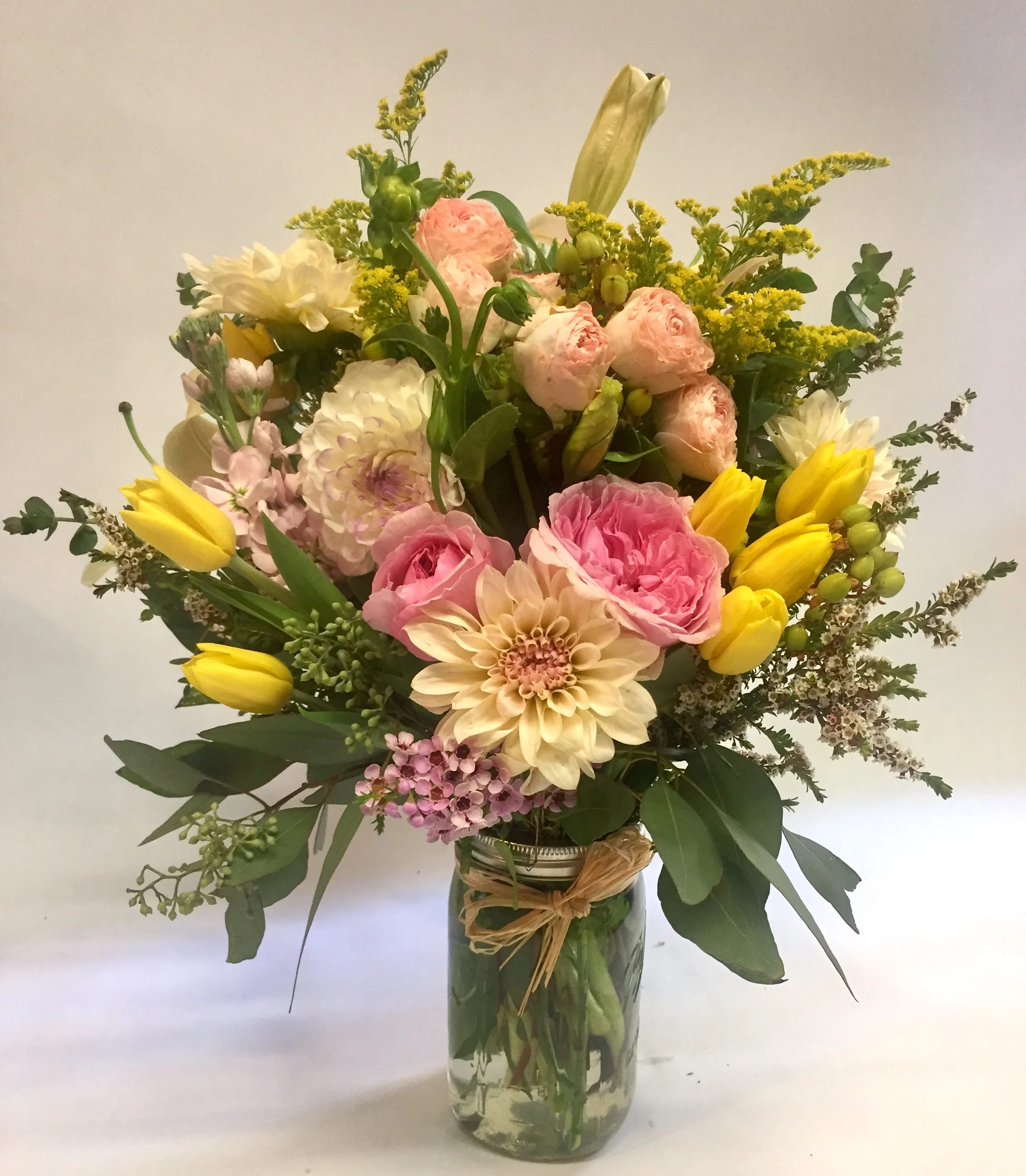 Just Angelic Jar - A sweet and soft arrangement in an over-sized mason jar. Featuring pink roses, tulips, spray roses, stock, solidago , lilies,  and other seasonal greens and filler. (Some flowers may be subject to change depending on the season. We will contact you with available flower substitutions; please contact us with specific questions if you are concerned with flower availability, thanks.) Featured Arrangement: $100.00