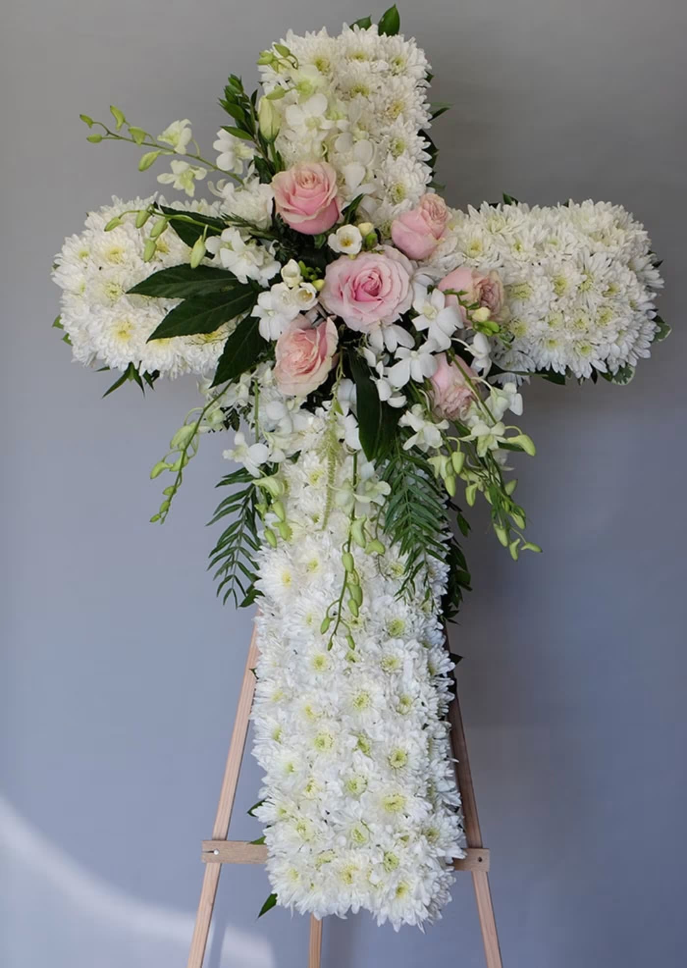 Love From Above Cross - This White Cross (30", 36" to 45") with cushion mums, lavender and cream roses, and dendrobium orchids is a beautiful and peaceful tribute to a loved one. The combination of soft colors and delicate flowers create a sense of serenity and comfort. It is a perfect way to express your condolences and show your love and respect. The size of the cross can be customized to fit the occasion and space.