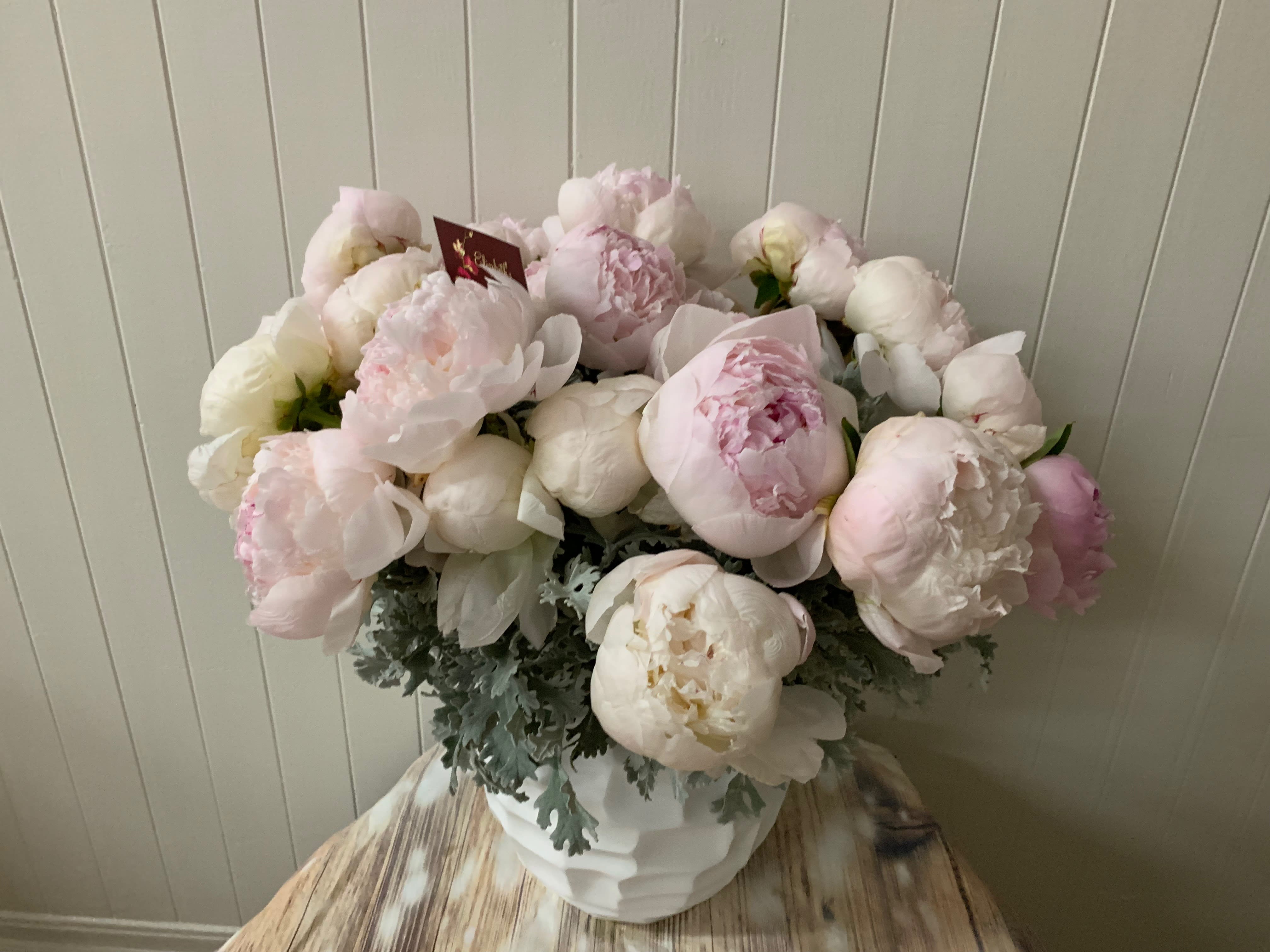 Two Dozen Blush Peonies in a Vase - Two dozen (24 stems) of blush-colored peonies, presented in a ceramic vessel. Peonies included will be in various stages of openness. Vases will vary.  *Precise shades of pink may vary depending on market availability.  **Each bouquet is unique and design style may vary slightly.