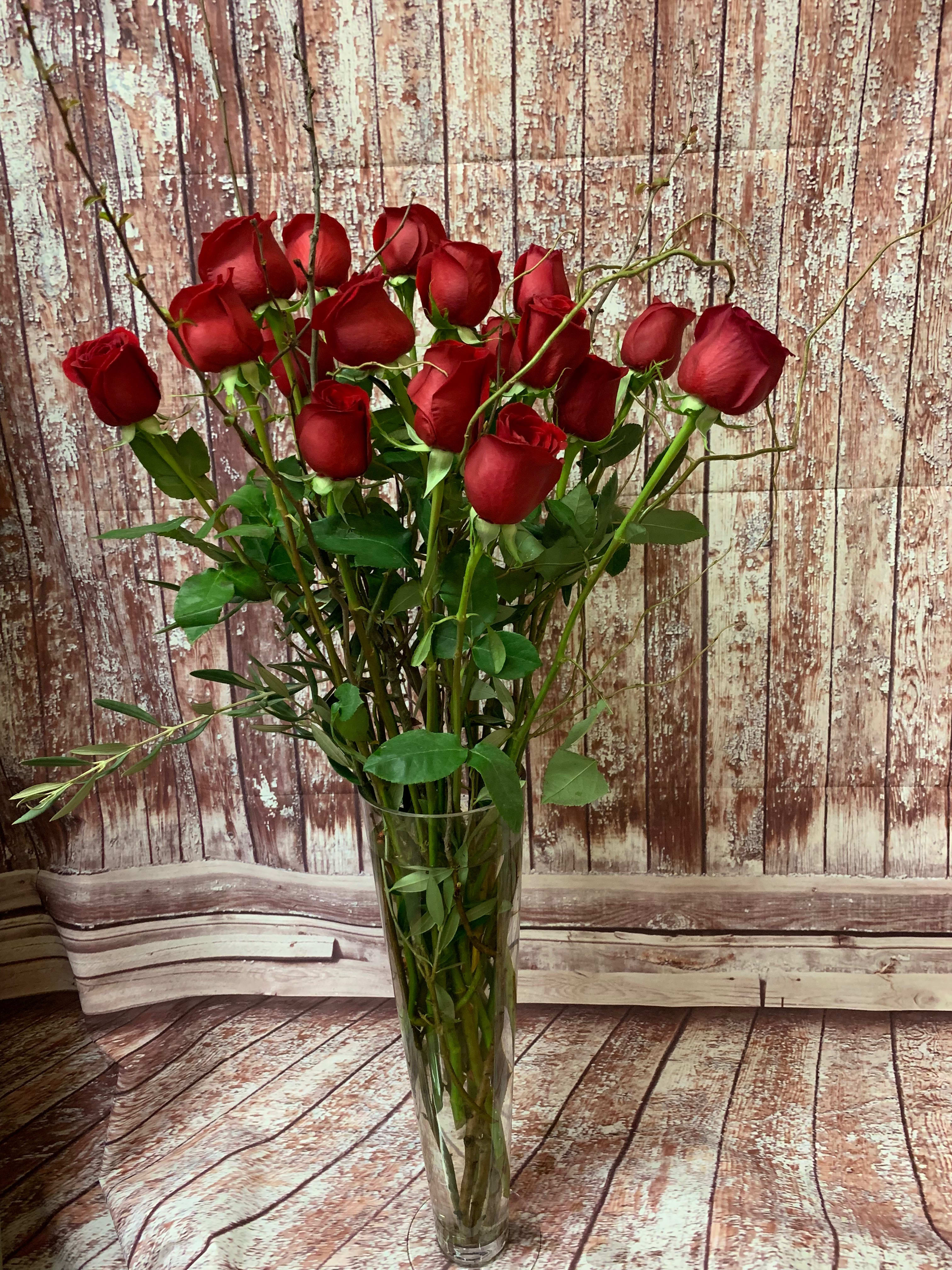 Eighteen Red Roses in a Vase - Eighteen long-stemmed red roses, presented in a clear glass or ceramic vase, and accented with hints of foliage.  *Vases and foliage may vary.  We have roses available in pink and white as well - if you would prefer a color other than red, please let us know in the Florist Instructions box at checkout.  **Each bouquet is unique and design style may vary slightly.