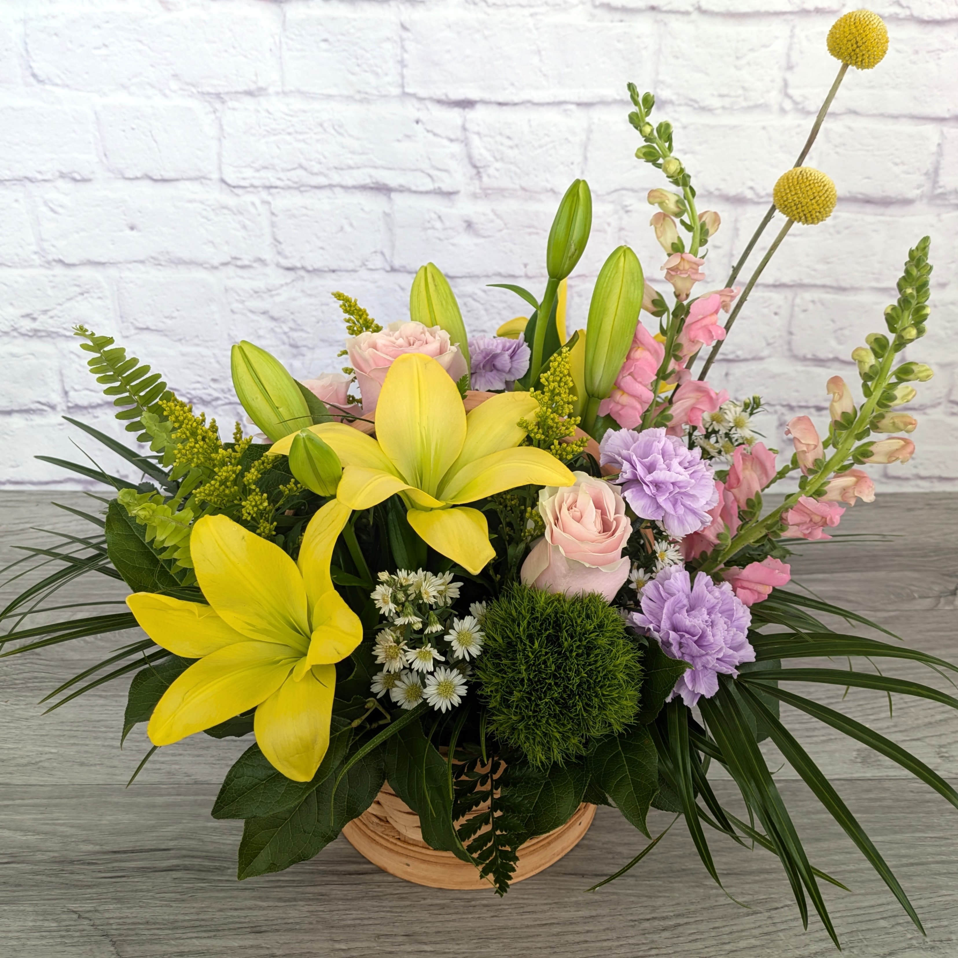 New Beginnings - New Beginnings is A Ladybug Floral exclusive bouquet. This bouquet features lilies, snapdragons, carnations, roses, dianthus and assorted accent flowers and greenery. All featured in a classic 8.5” Basket.   Orientation: All Around 17” Tall 24” Wide  