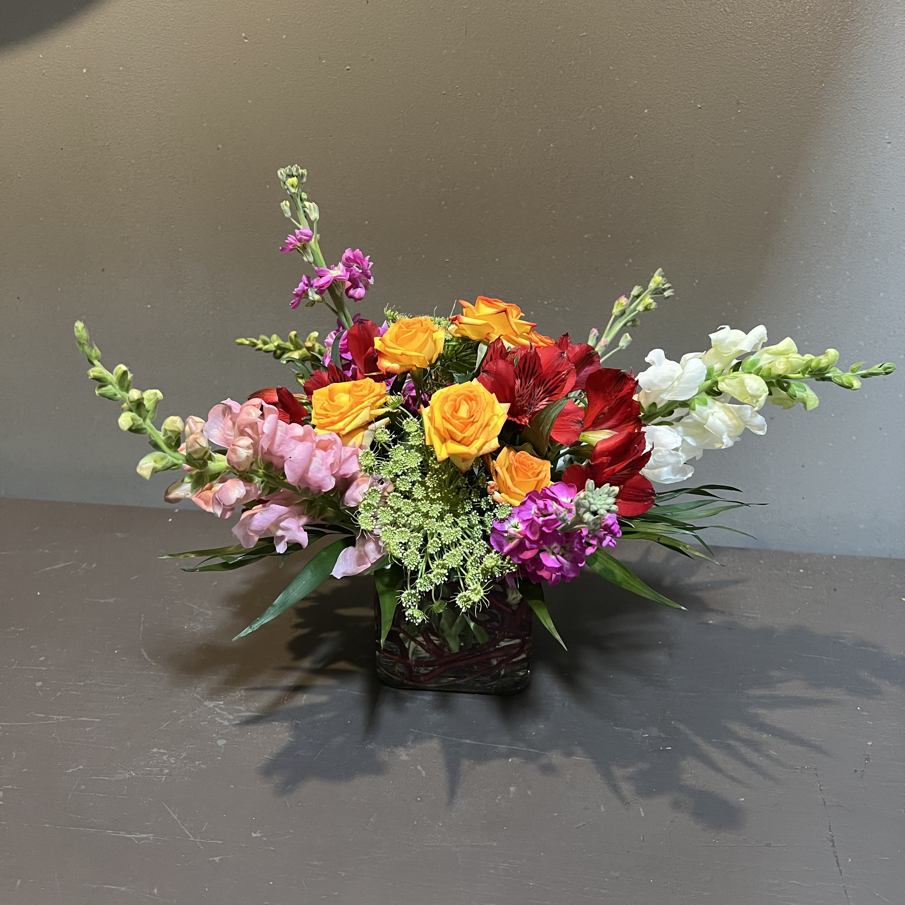 Spunky Spring - A flirty, contemporary bouquet in spring colors!  Measures approx. 12"Tx16"W and arrives in glass cube.