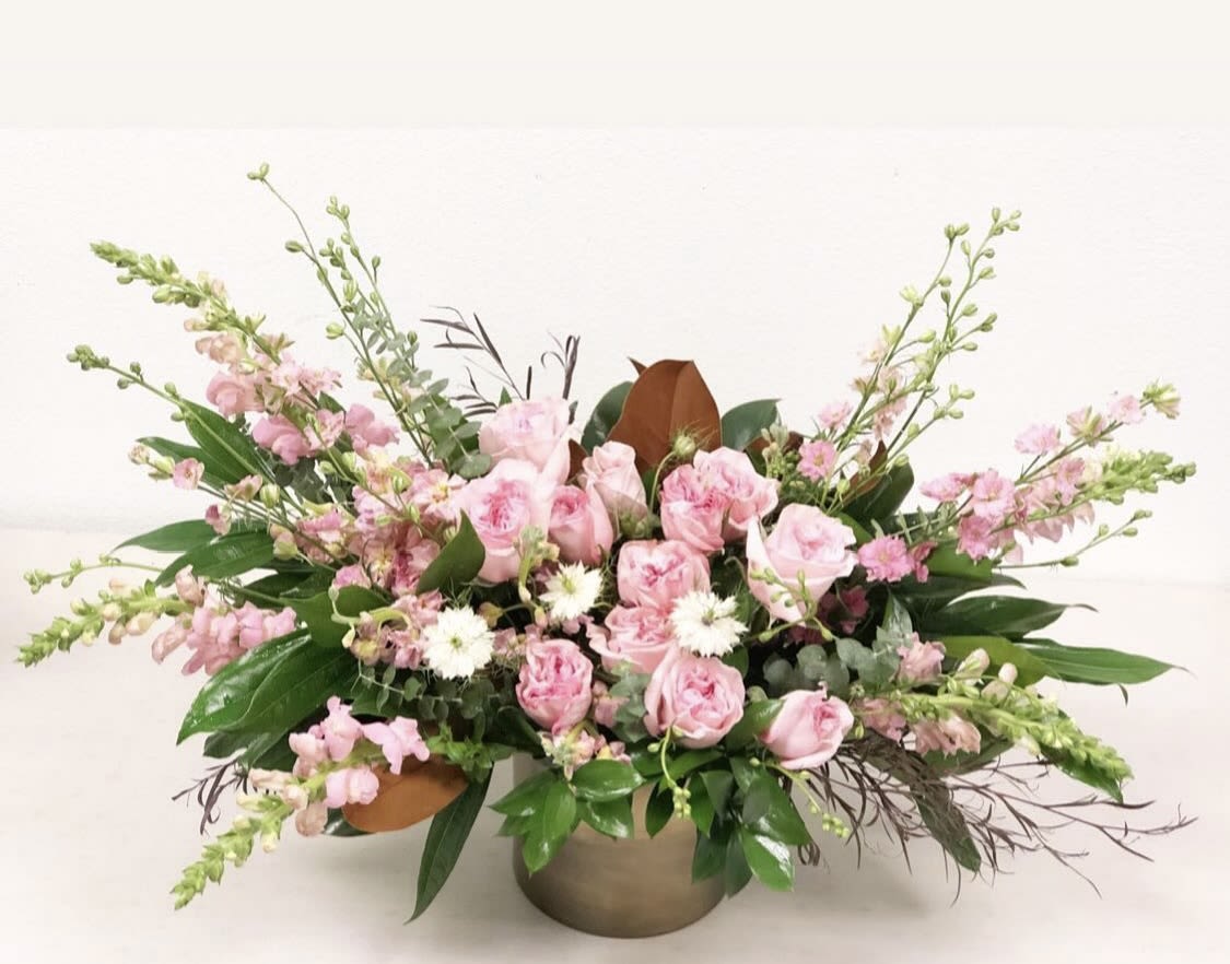 Pink Paradise -  Pink Paradise Arrangement  Welcome to Pink Paradise—where flowers live large, bold, and unapologetically fabulous. Bursting with shades of pink in every tone imaginable, this design is a celebration of beauty, confidence, and joy. Seasonal foliages and glossy magnolia leaves add depth and texture, making this arrangement feel both lush and luxurious. It’s playful yet sophisticated, dramatic yet refined—the ultimate floral statement for anyone who believes life is better in pink. Guaranteed to bowl over any pink lover, this arrangement is more than a gift—it’s a luxury experience in full bloom. 