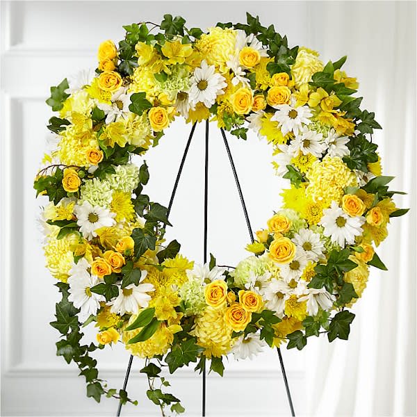 Golden Remembrance Wreath - Whether yellow was their favorite color or it captures the essence of their radiance, a ring of bright blooms thoughtfully displays your sentiment. Our Golden Remembrance Wreath is composed of spray roses, daisy pompons, carnations and more. Each flower is selected to beautifully accent one another and the love you are sending.