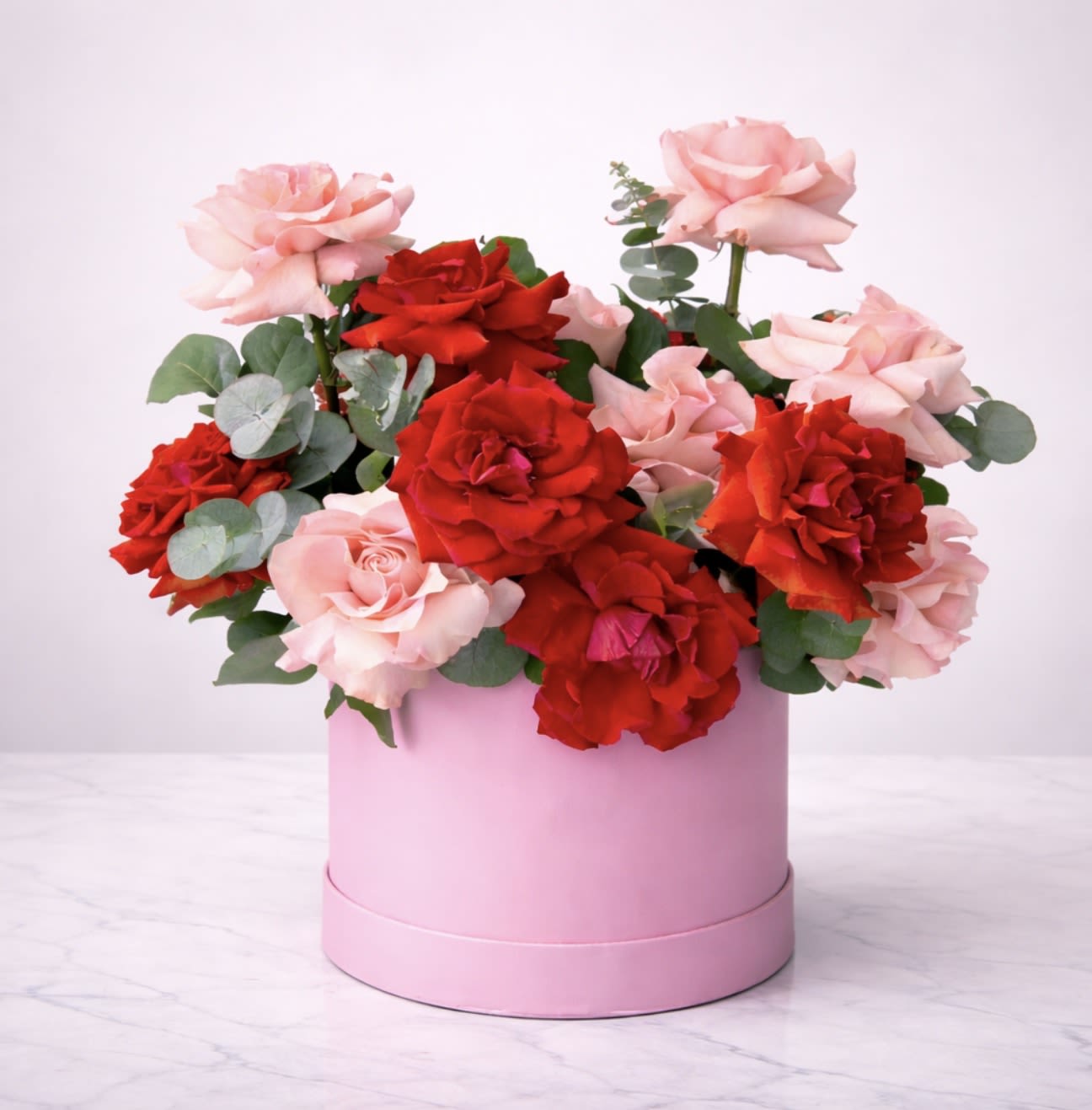 Blush &amp; Scarlet Elegance - Experience timeless romance with our Blush &amp; Scarlet Elegance, a luxury rose arrangement featuring premium red and blush pink roses beautifully designed in a soft pink hat box. Accented with fresh eucalyptus, this elegant floral gift is perfect for anniversaries, birthdays, Valentine’s Day, and special celebrations.
