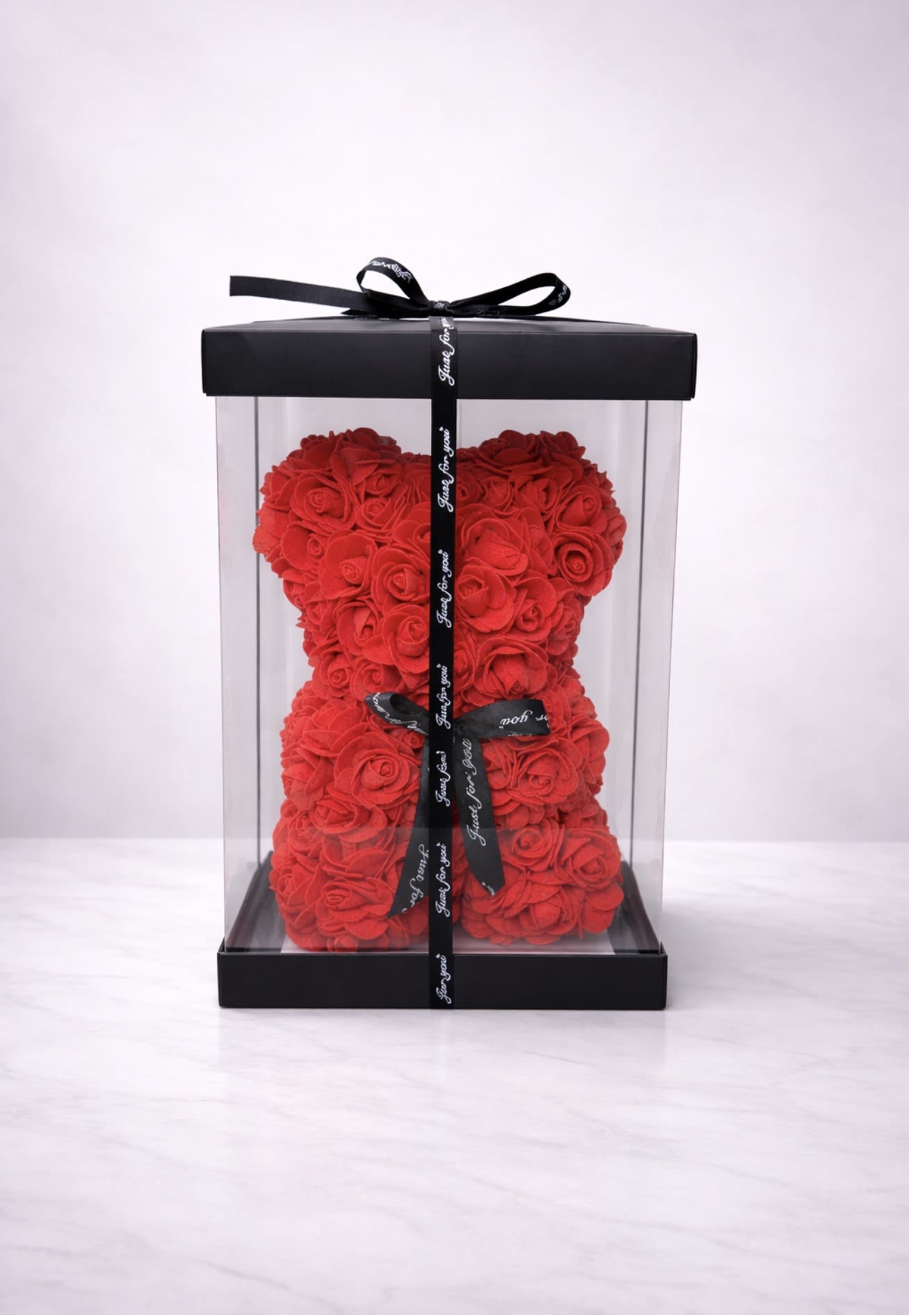 Crimson Forever Rose Bear - A 10” stunning red rose teddy bear handcrafted from premium faux roses and elegantly presented in a sleek clear display box with a black satin ribbon. This long-lasting keepsake is a timeless symbol of love and passion — perfect for anniversaries, Valentine’s Day, birthdays, or a romantic surprise. A luxury gift that makes a bold and unforgettable statement. 