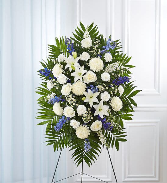 Blue And White Standing Spray-Small - Standing spray arrangement with white roses, Asiatic lilies, football mums, carnations and monte casino; blue delphinium; accented with soft, lush greenery