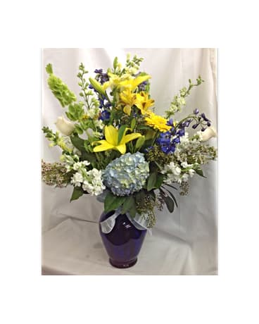 Joyous Celebration Bouquet - In this hand arranged bouquet there are blue Hydrangea, blue Delphinium, yellow Snap Dragons, white Stock, white Larksburg, yellow Lilies, white Roses, Bells Of Ireland, yellow Gerber Daisies.  All flowers and colors are subject to change due to availability.    FCF-0279