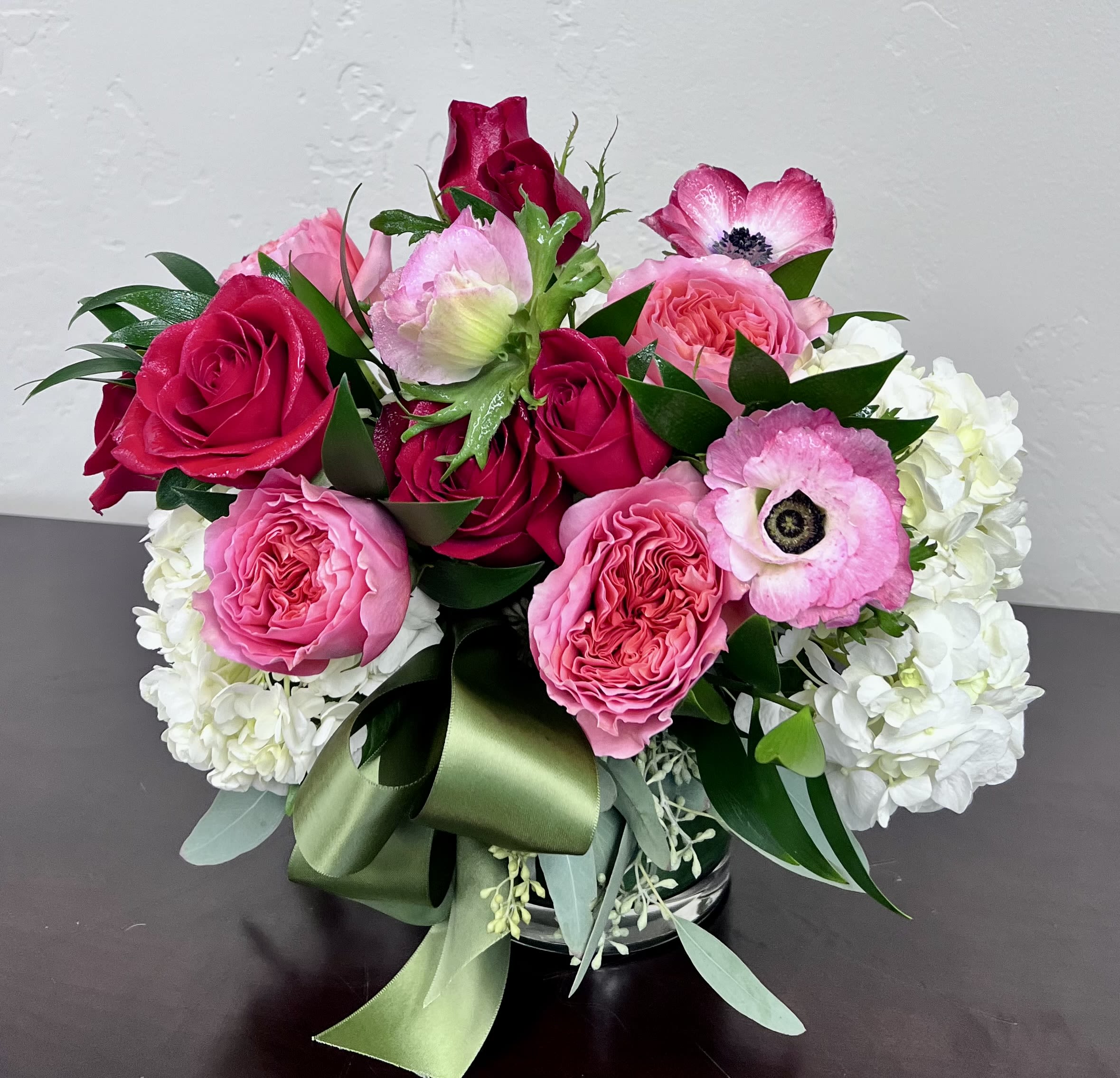 Petals and Promise - Celebrate the feeling of spring’s first warm morning with Petals &amp; Promise — a lush gathering of vibrant roses, delicate anemones, and soft hydrangea designed to look as though it was just picked from the garden. Accented with seasonal greenery and finished with a soft satin ribbon, this arrangement brings effortless freshness and natural beauty into any space. Perfect for birthdays, celebrations, or simply brightening someone’s day with the uplifting spirit of the season.