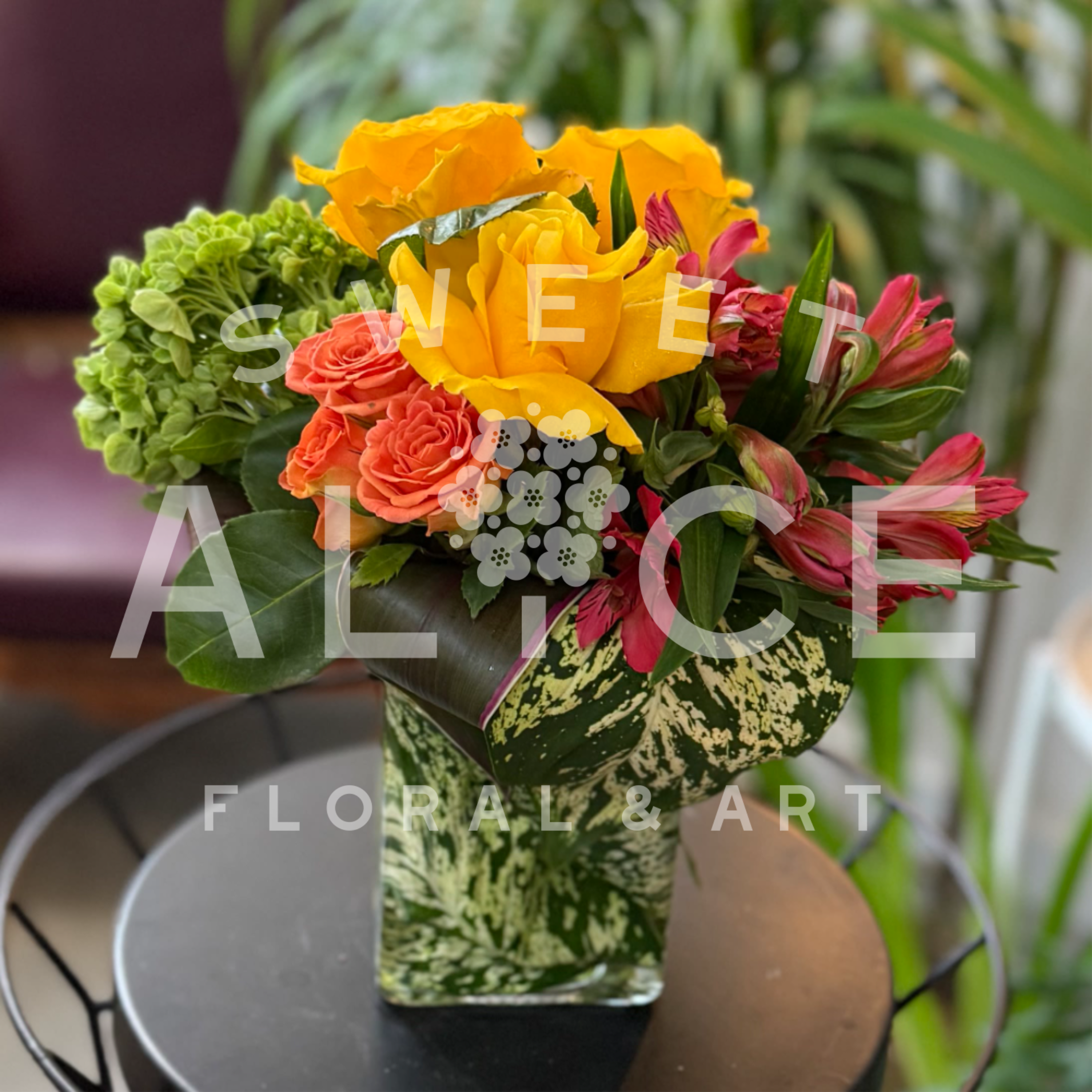 Bold and Bright - This marvelous arrangement of pinks, yellows, oranges and greens is sure to knock your socks off! Roses, spray roses, alstroemeria, hydrangea and bold tropical foliage star in this arrangement.