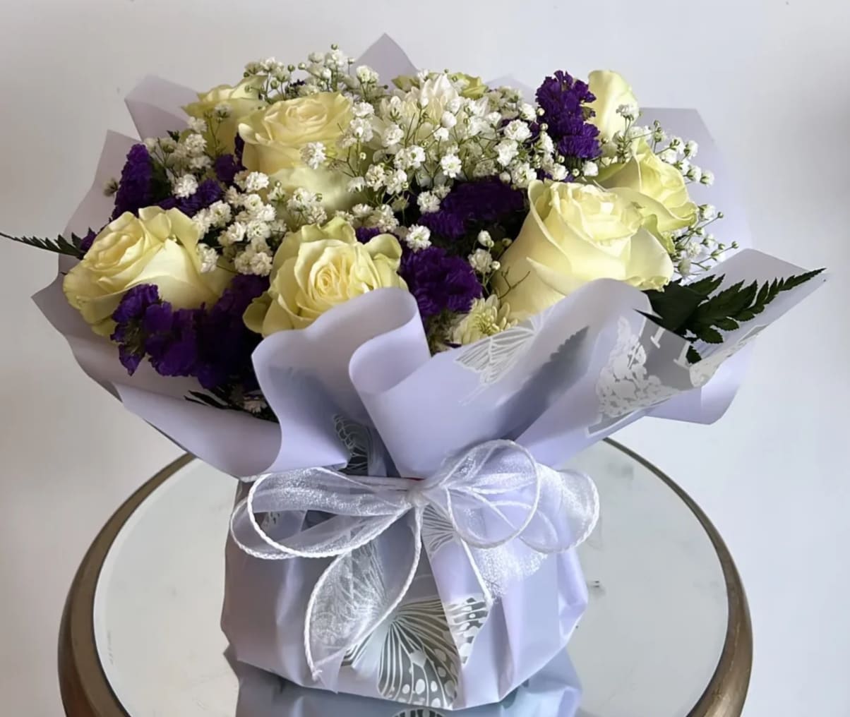 Purple Smiles Arrangment - -The bouquet is composed primarily of delicate white roses, purple statice and baby's breath, creating a harmonious blend of colors and textures.