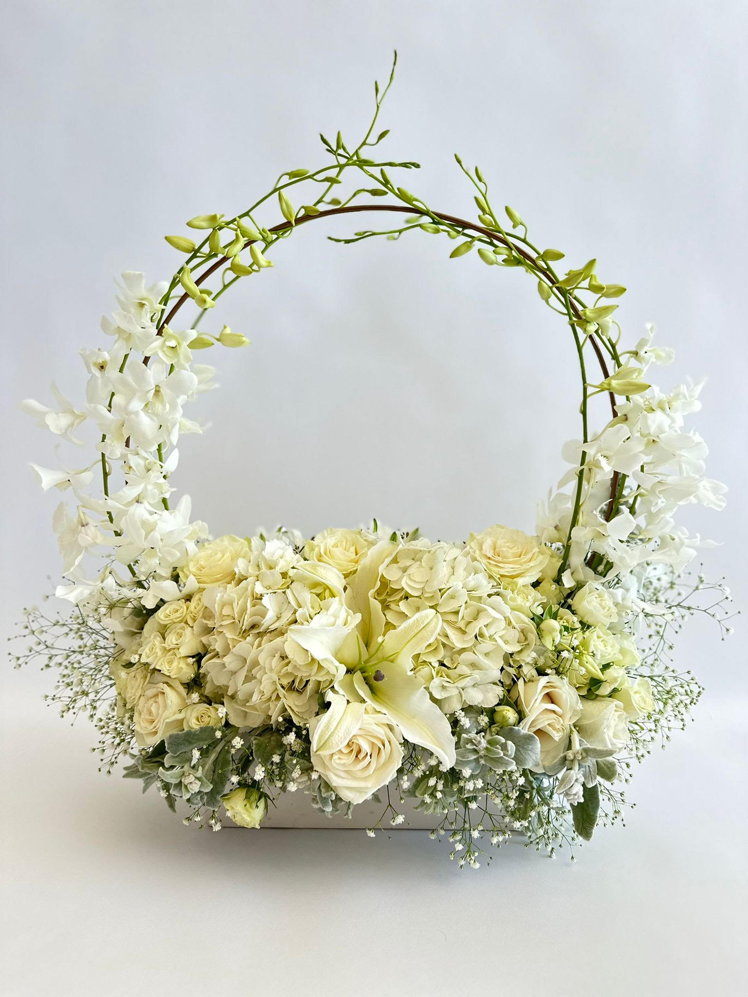 White Ocean - Introducing an exquisite arrangement of pure white florals, elegantly presented in a long horizontal vase. This arrangement features pristine white roses, lush hydrangeas, and lilies, each bloom radiating beauty and refinement. The flowers are arranged with sprigs of baby's breath and delicate greens, adding natural purity. This floral masterpiece releases timeless beauty and sophistication, perfect for adding a touch of elegance to any setting.