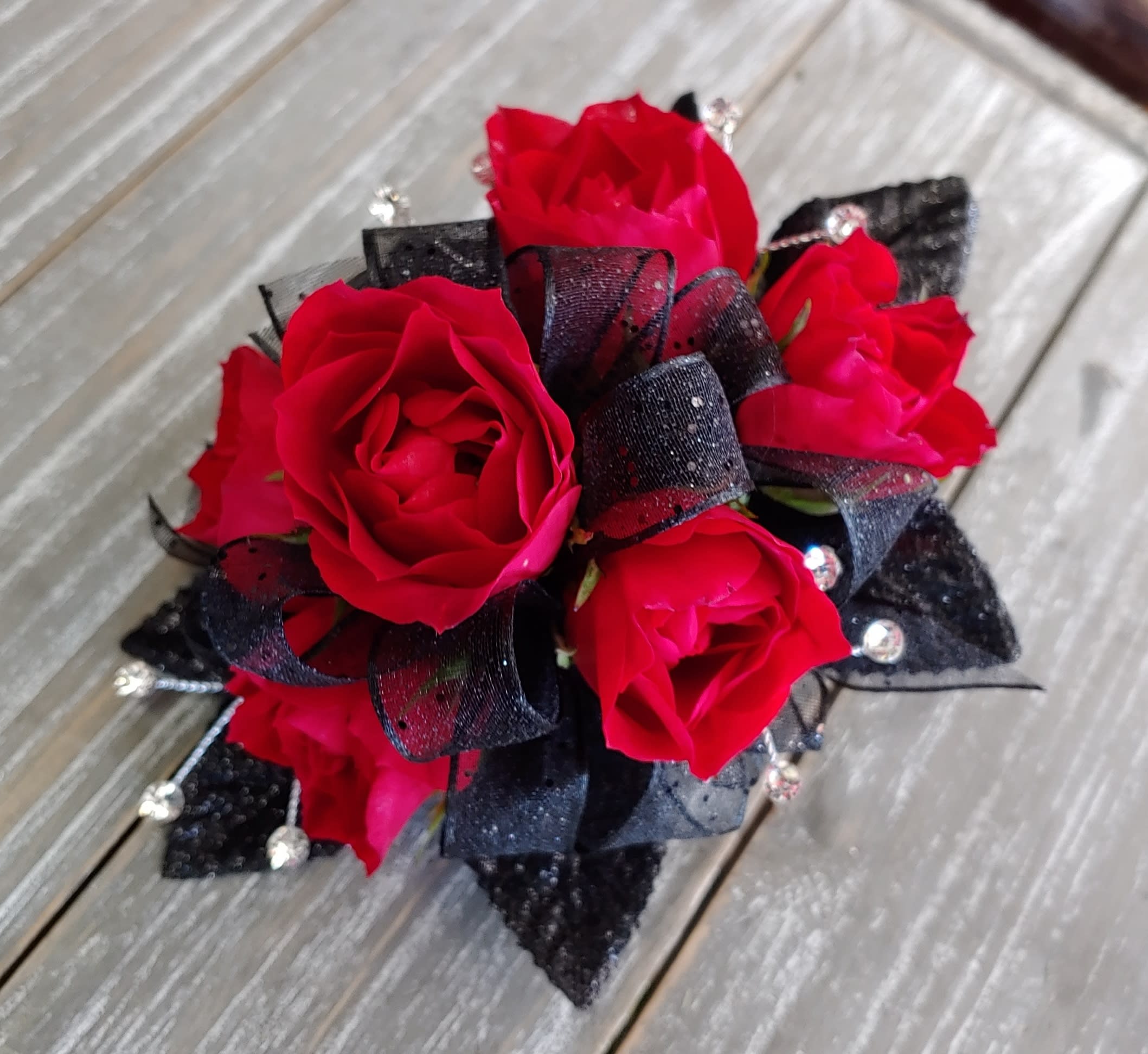 Red  Mini-Rose Wrist Corsage - Miniature red roses, black sparkly ribbon, and rhinestones.  This item is available for pickup only. Please call for availability.
