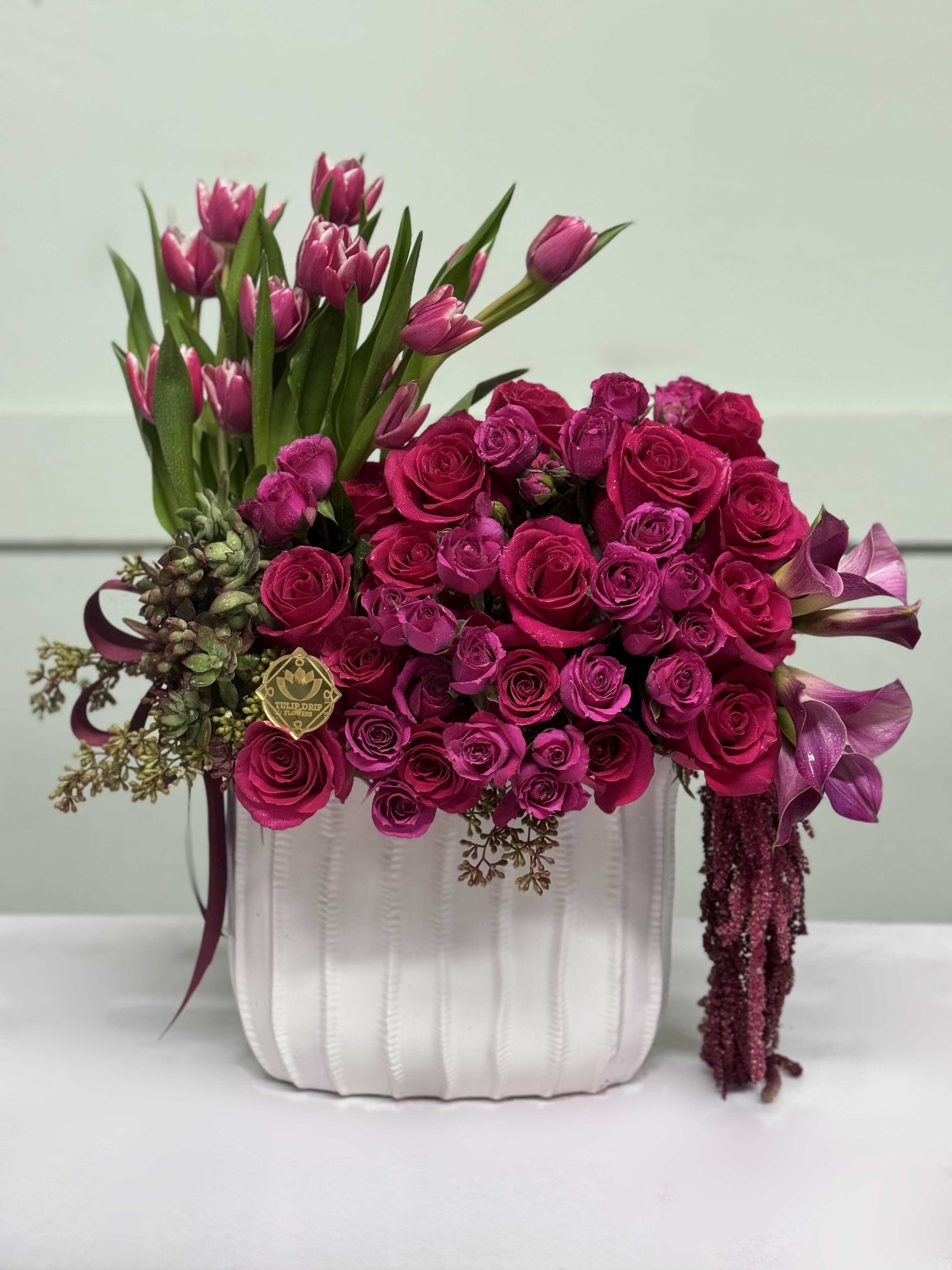 Berry Bloom Box  - A luxurious mix of fuchsia roses, deep pink tulips, calla lilies, and succulents arranged in a white ceramic box. Bold, vibrant, and unforgettable – just like mom.