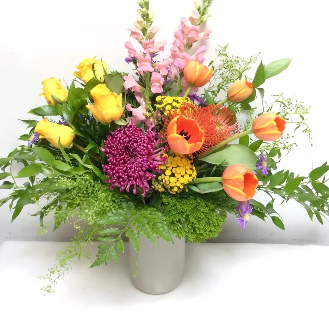 Sylvia's Garden by Hudson Flower Shop - Bring your favorite garden flowers indoors with this vibrant design arranged in a trendy corrugated metal vase.  Blooms featured are roses, chrysanthemums, viburnum, fever few, tulips, tropical protea and more. 