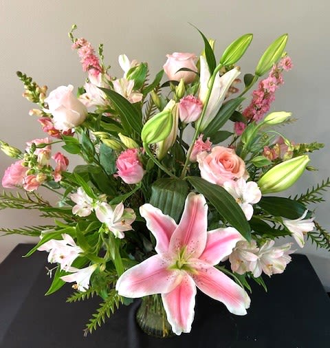 Pink lilies and roses arranged in a glass vase