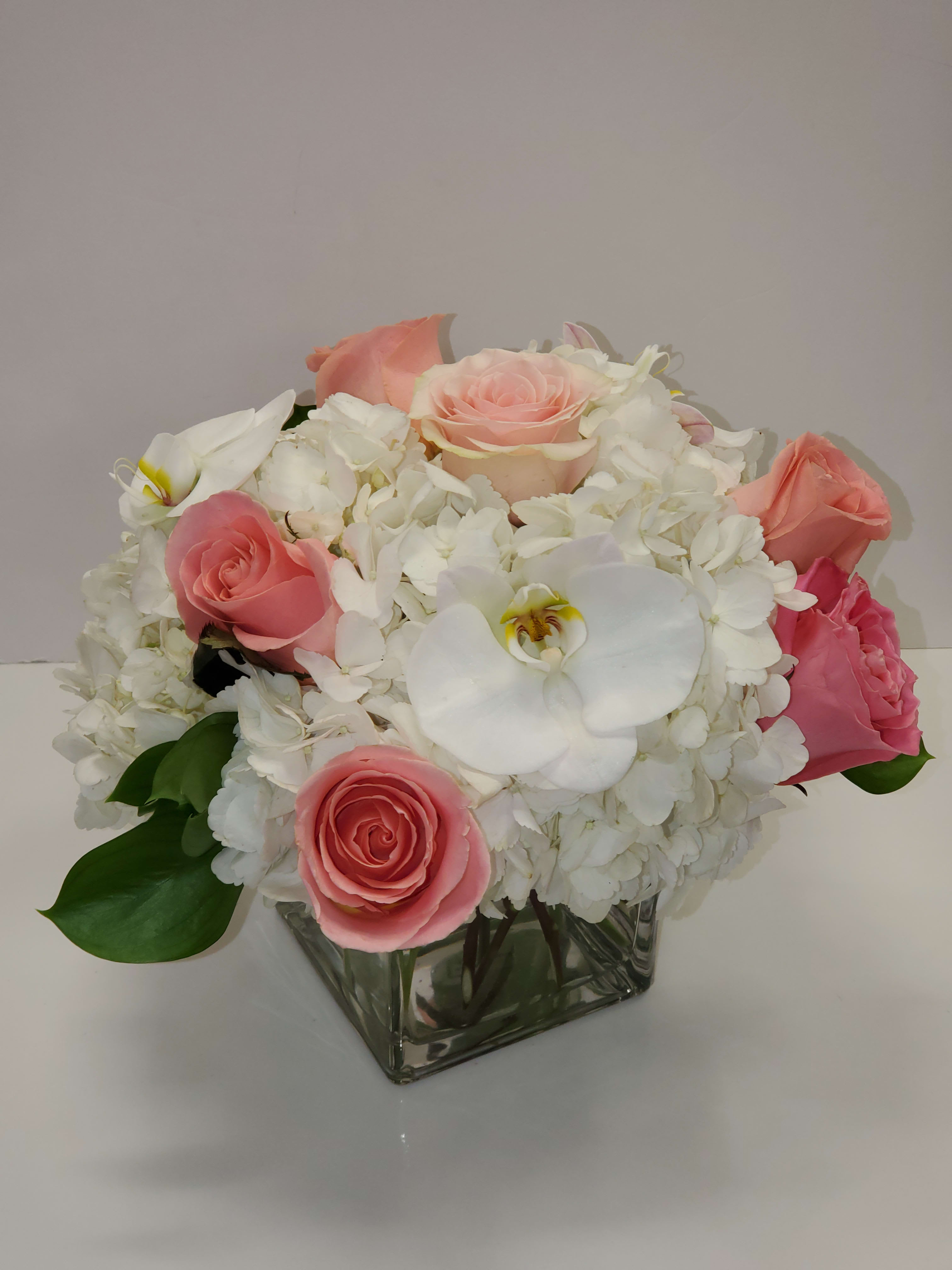 Elegant by Manny - This bouquet shows that there is beauty in simplicity. Elegant by BloomNation™ is the perfect gift for almost any occasion, especially for celebrations and showing gratitude.    Arrangement Details: Includes white roses, blush pink roses, white cymbidium orchids, and white hydrangea. APPROXIMATE DIMENSIONS:10" H X 11" W X 11"L